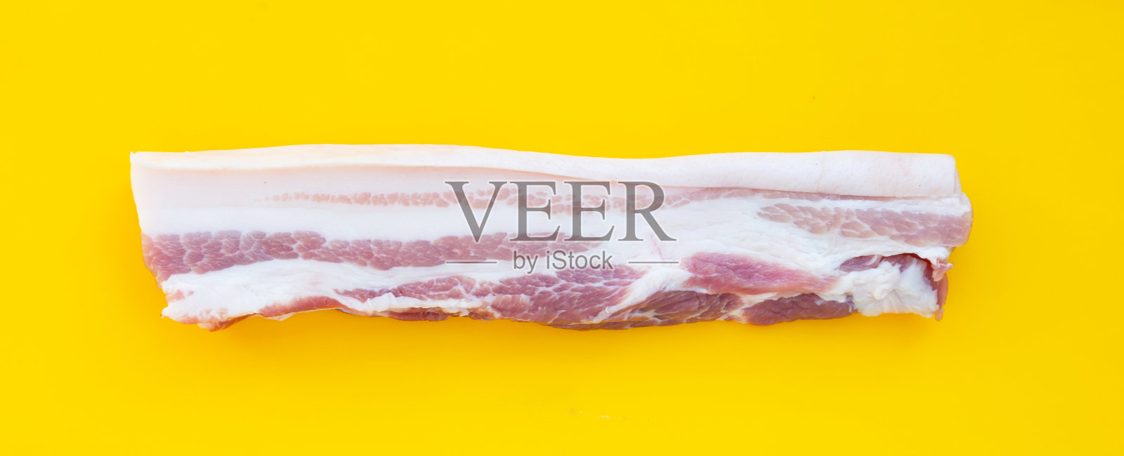 白盘子里的条纹猪肉，背景为黄色。照片摄影图片