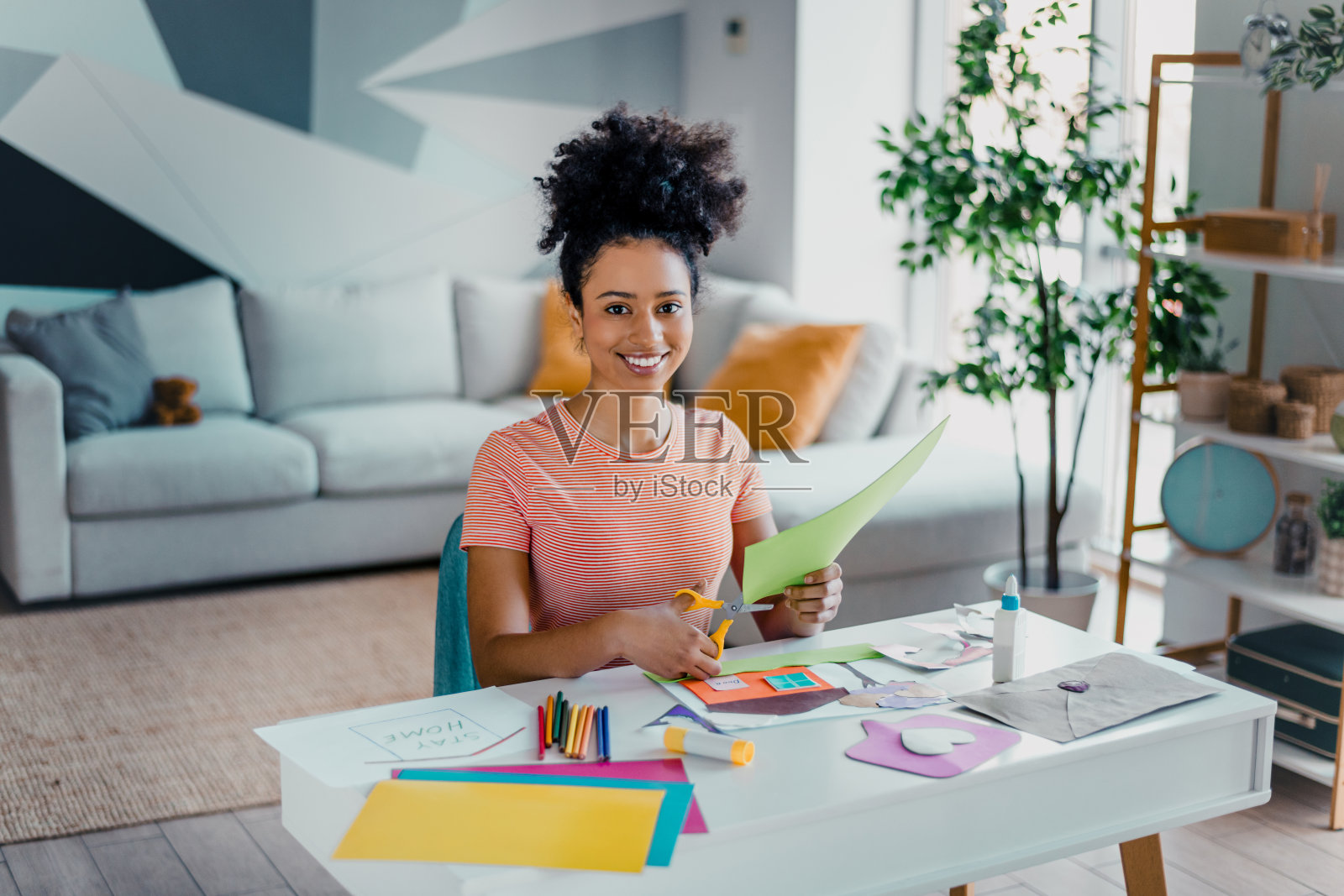 年轻女性在现代客厅的白天享受手工艺活动，强调创造力和放松。照片摄影图片