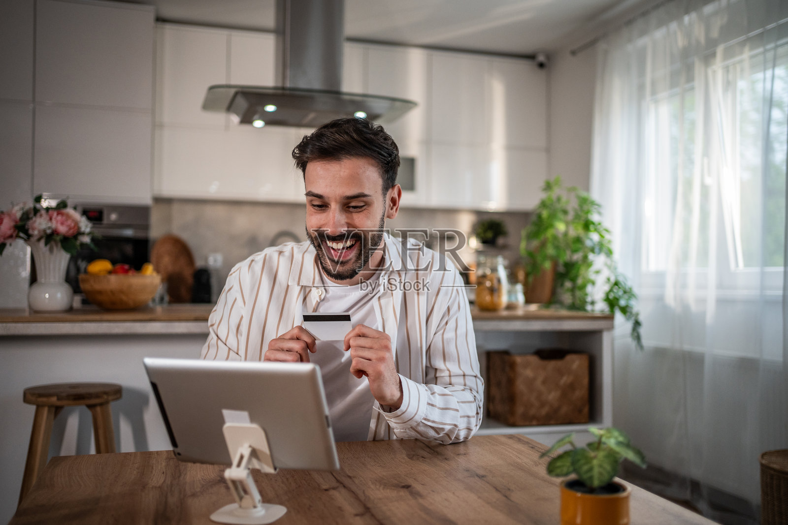 快乐的男人在家中使用数字平板和信用卡进行在线支付照片摄影图片