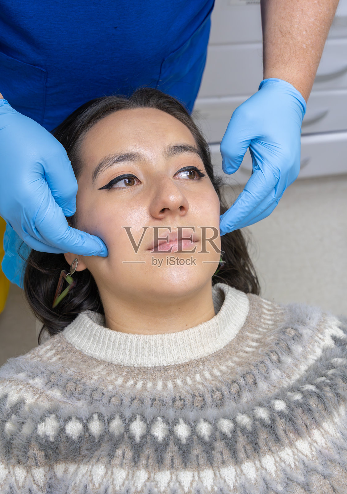 牙医在诊所检查年轻女性的面部和下颌照片摄影图片