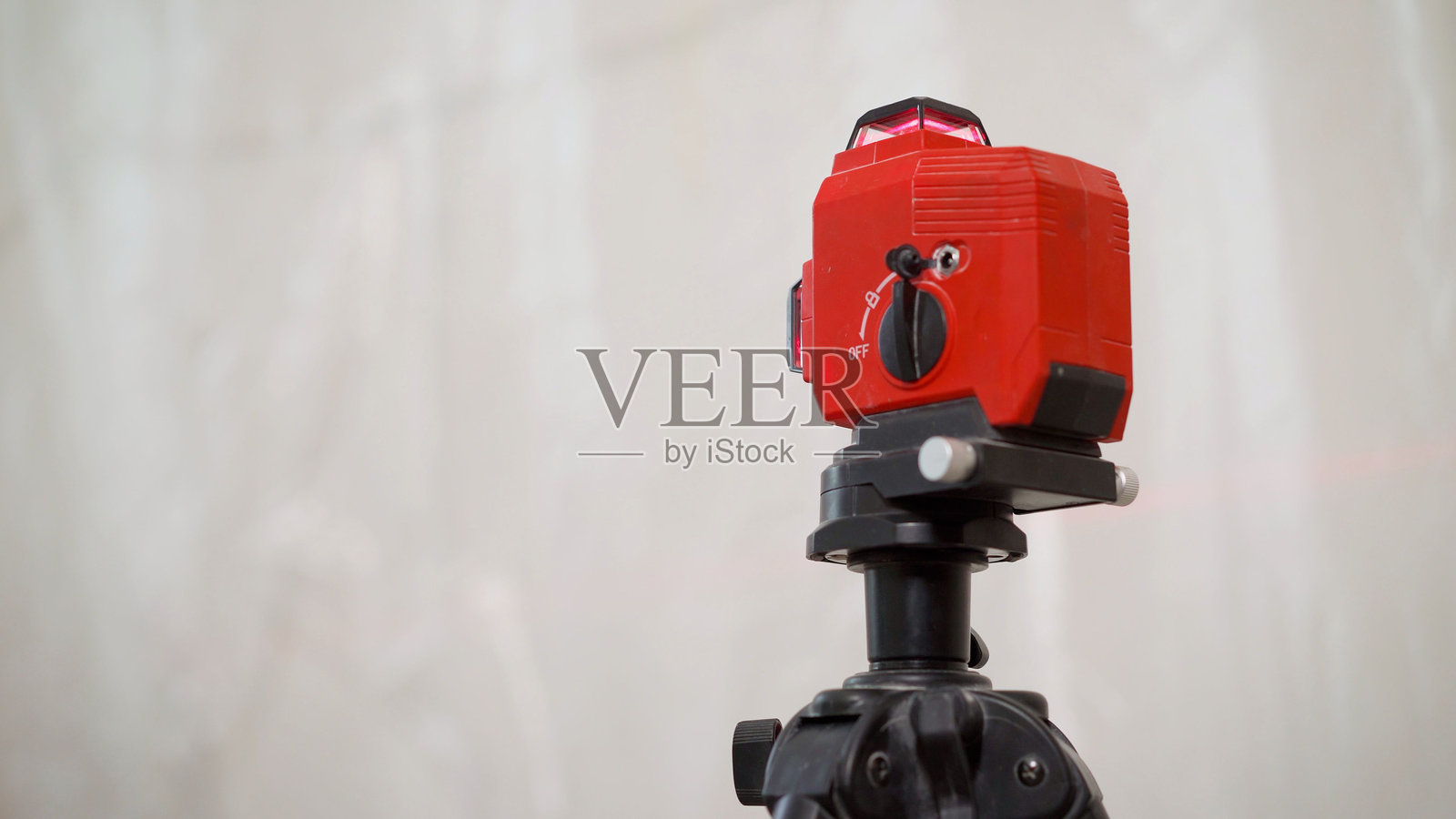 建筑激光水平仪与墙壁背景。公寓装修和施工工作。用于公寓装修的激光水平仪。使用激光水平仪修理公寓，检查已完成公寓墙壁的垂直度。照片摄影图片