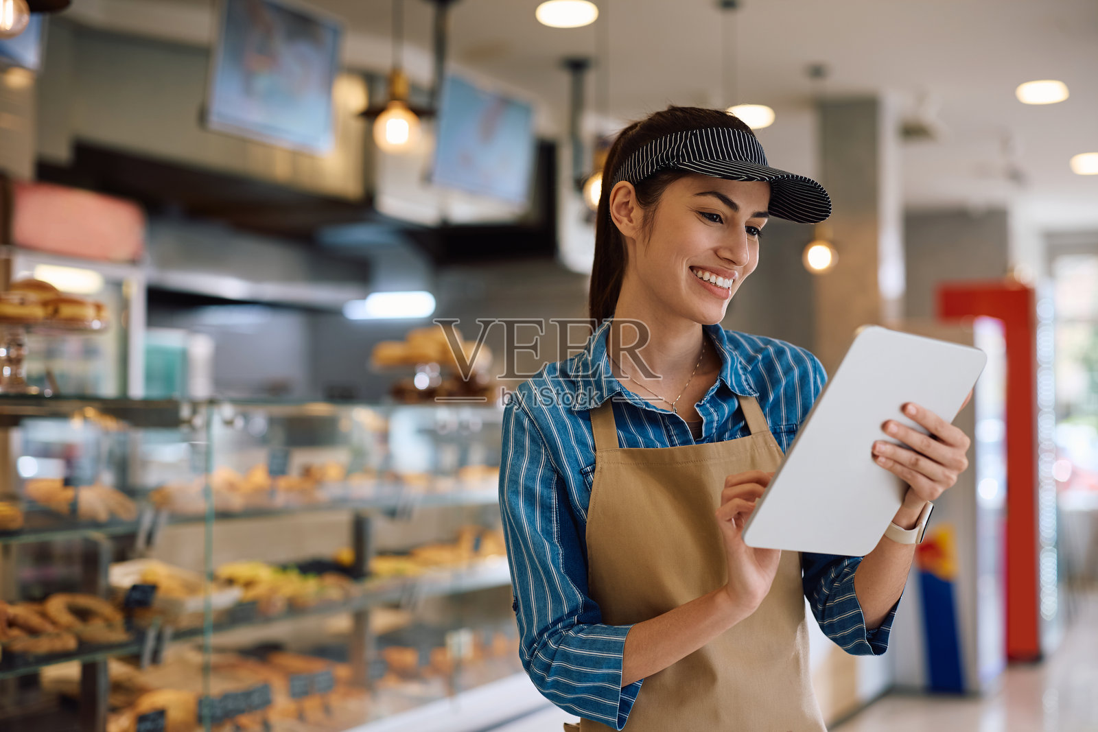 快乐的面包店老板正在使用平板电脑。照片摄影图片