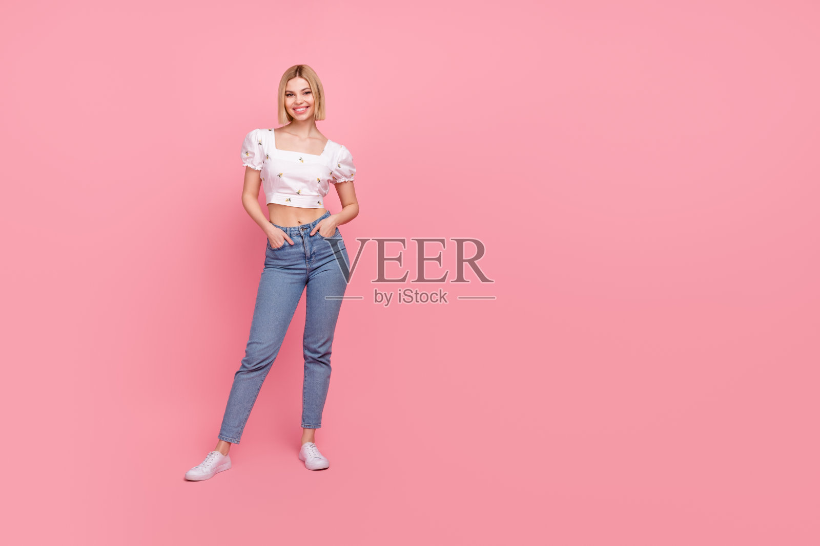 全身照，漂亮年轻女士在粉色背景前摆姿势，展示新衣服，穿着衬衫、牛仔裤和鞋子。照片摄影图片