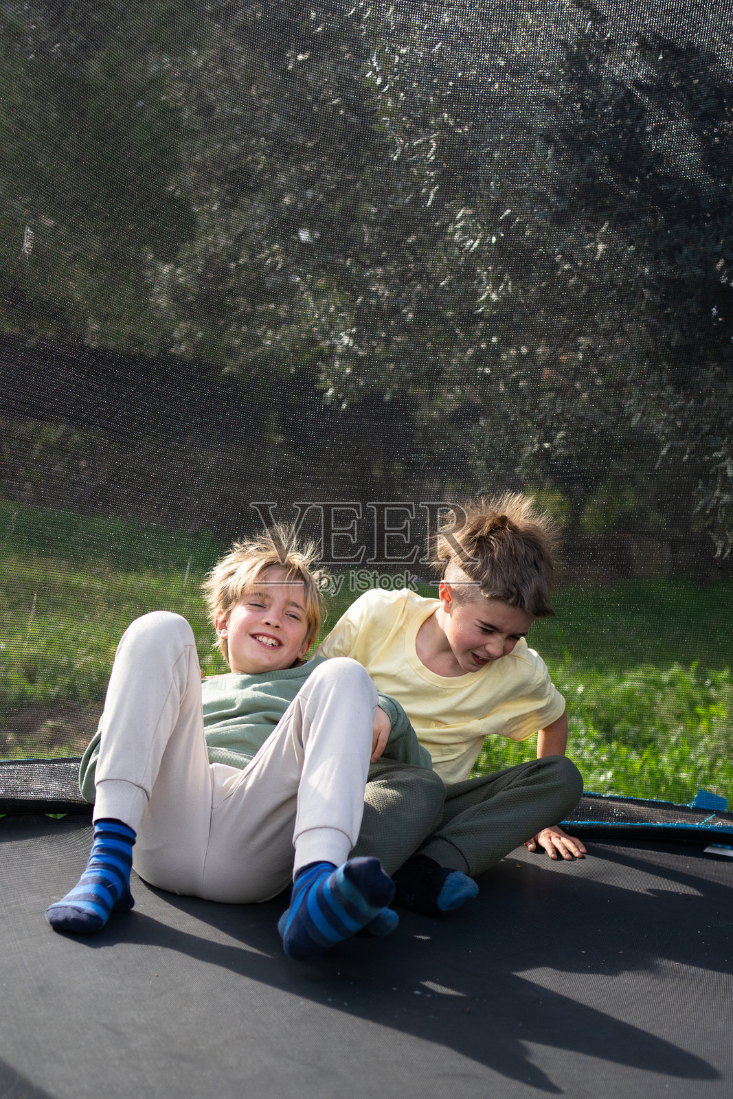 两个快乐的孩子在户外的蹦床上欢笑玩耍照片摄影图片