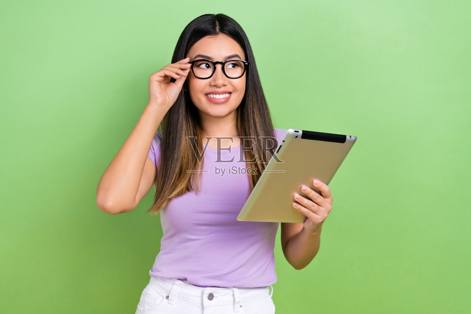 棕发韩国女商人手持数字平板，望向空旷的空间，招聘员工，背景为绿色。照片摄影图片
