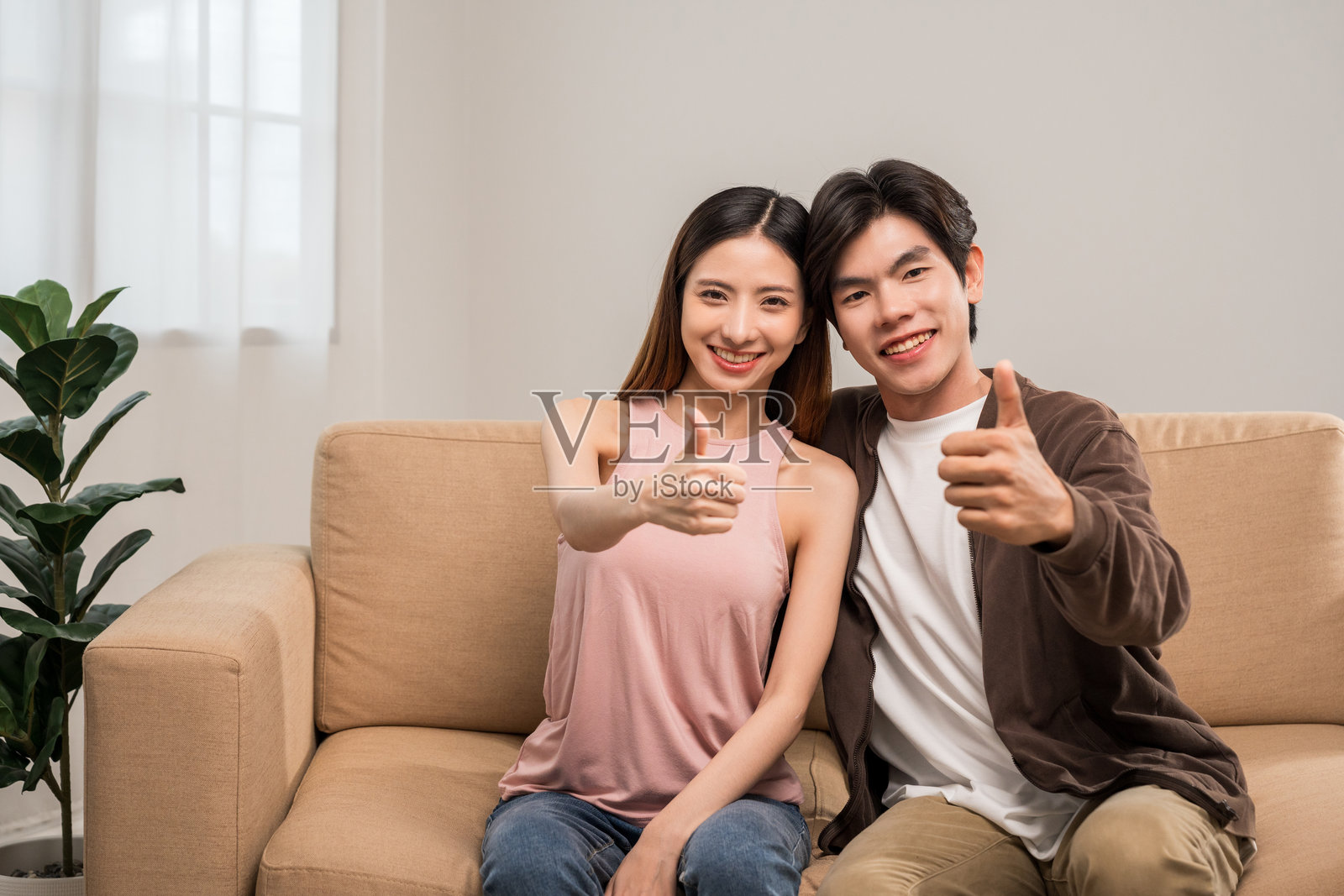 亚洲夫妻刚结婚，快乐地在客厅沙发上放松，购买新房。照片摄影图片