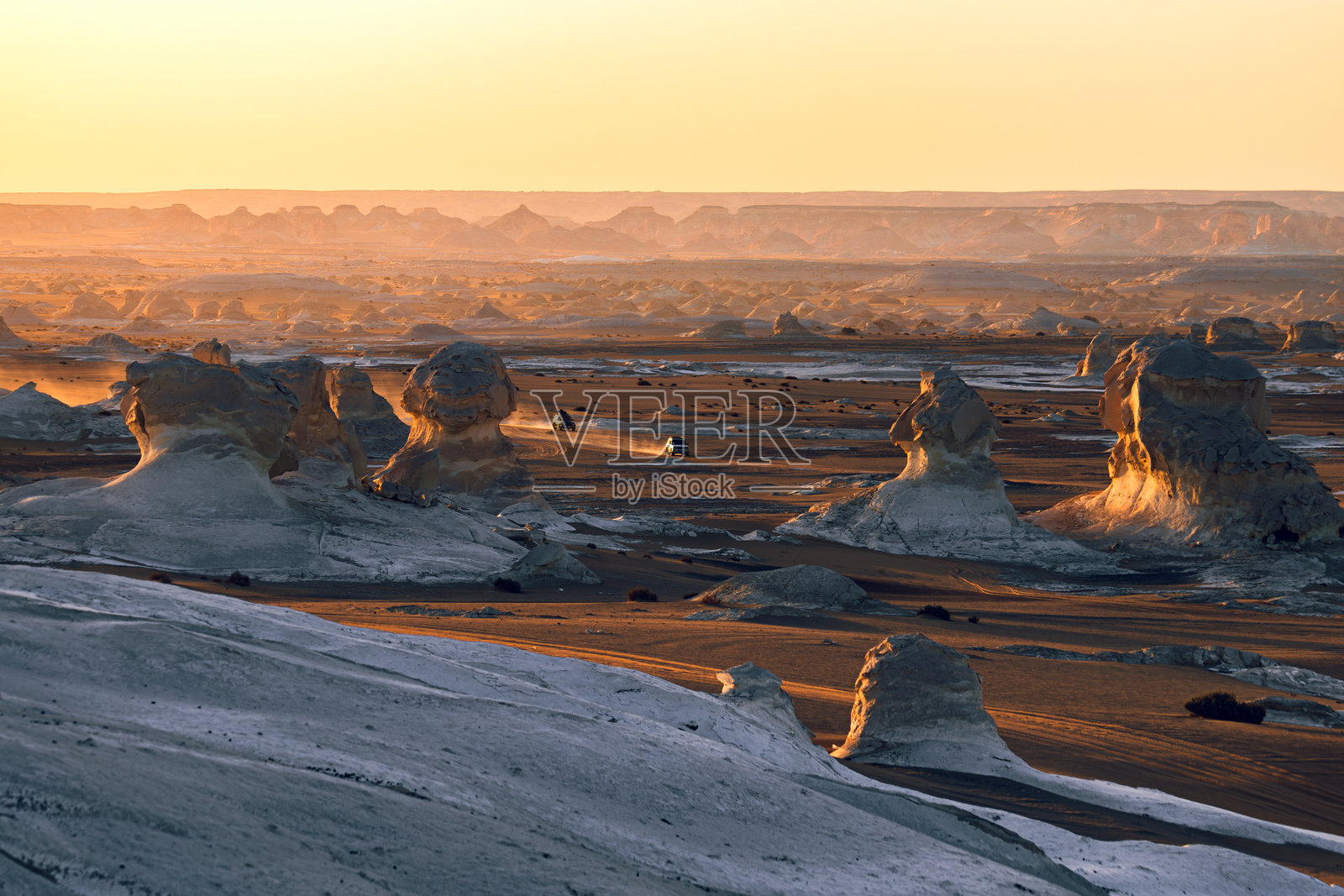 埃及白色沙漠的日落，伴随巡游的四驱车和闪烁的尘埃照片摄影图片