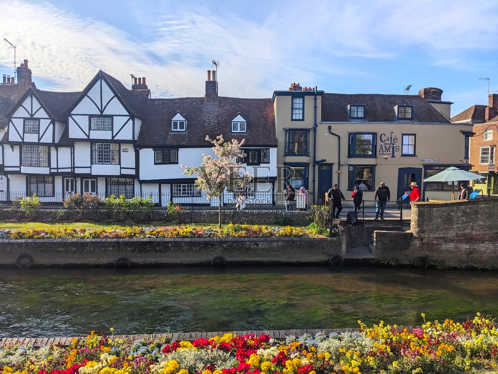历史悠久的都铎建筑和河流，五彩缤纷的春花以及人们在西门花园享受阳光明媚的坎特伯雷照片摄影图片