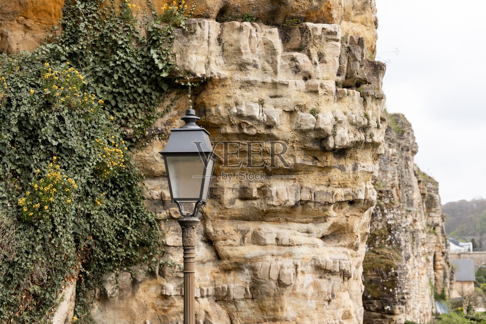 古老风格的中世纪街道照明，街灯杆矗立在石头路上，背景是城堡墙。照片摄影图片