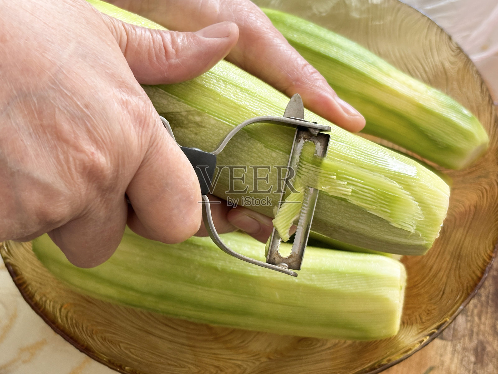 女性手在剥去西葫芦皮照片摄影图片