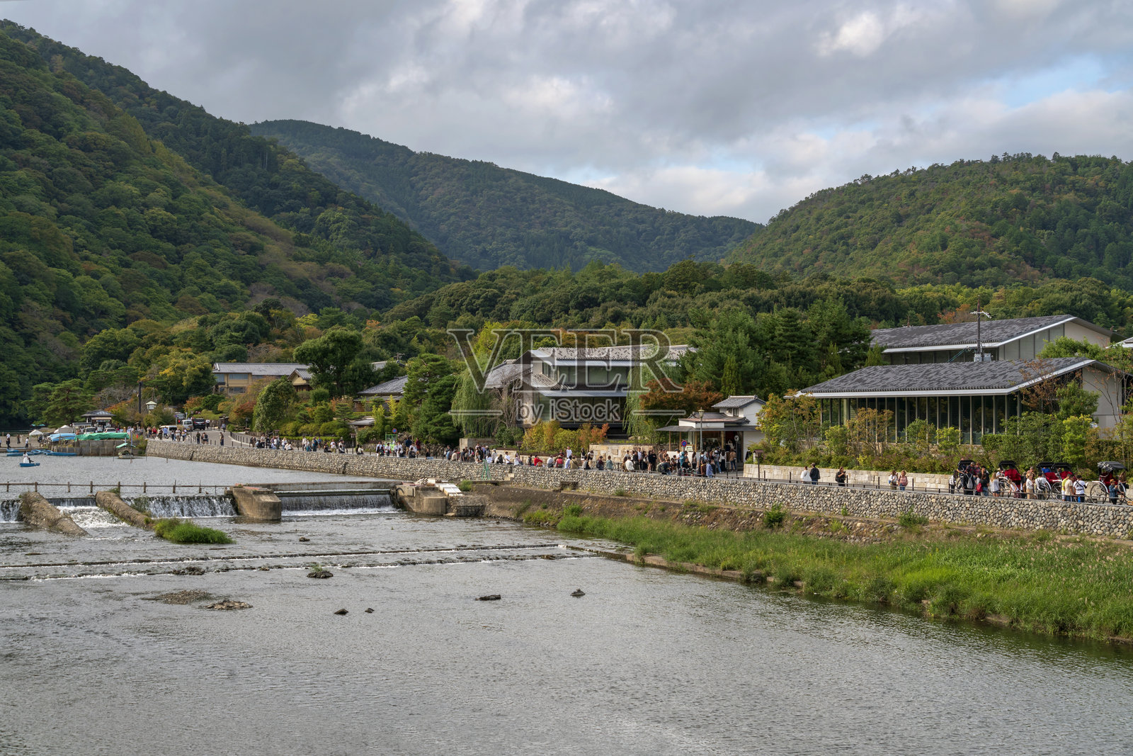 在日本京都的嵐山地区，阳光明媚的秋日里，居民们最喜欢的度假胜地——桂川的岚峡进行划船活动。照片摄影图片