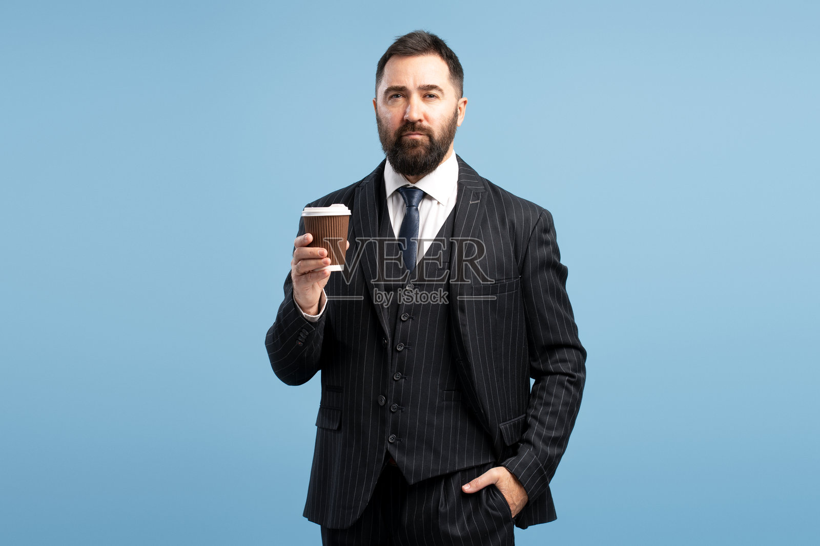 自信的商人手持外带咖啡杯，背景为蓝色照片摄影图片