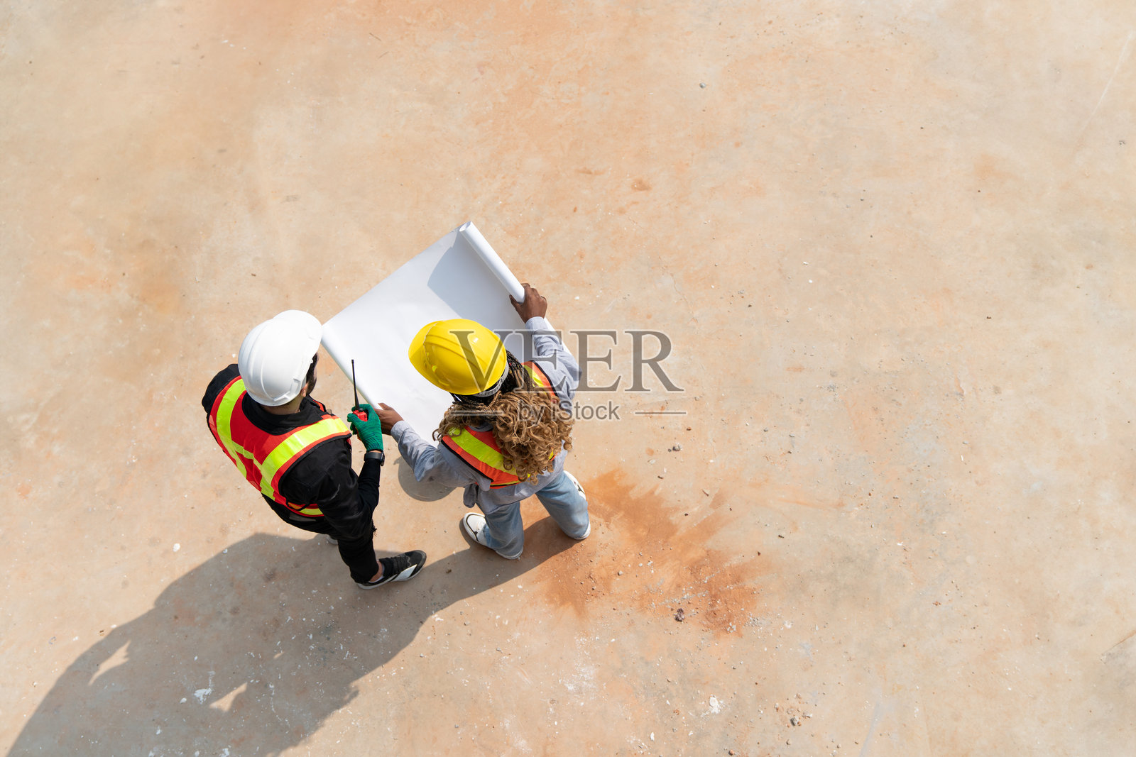 从上方俯视土木工程师和女建筑师在施工现场讨论建筑项目计划的蓝图。团队工头在开发计划会议上。照片摄影图片