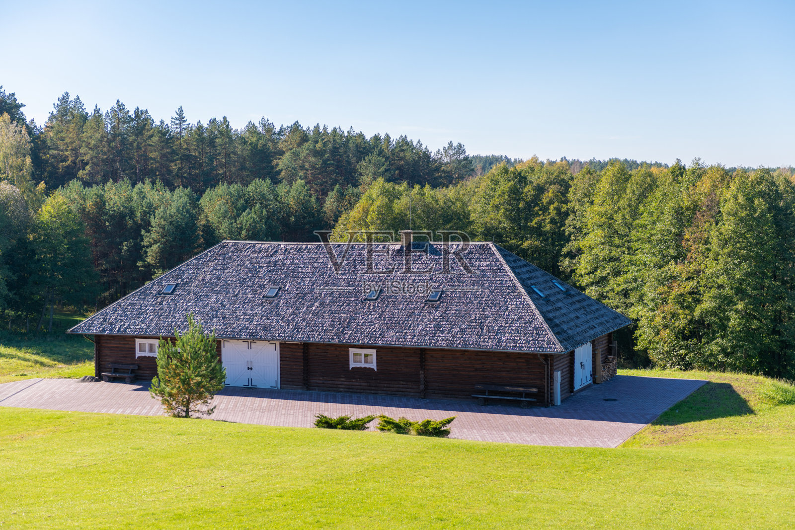 阳光明媚的日子里，四周被郁郁葱葱的森林环绕的乡村木屋或小屋照片摄影图片