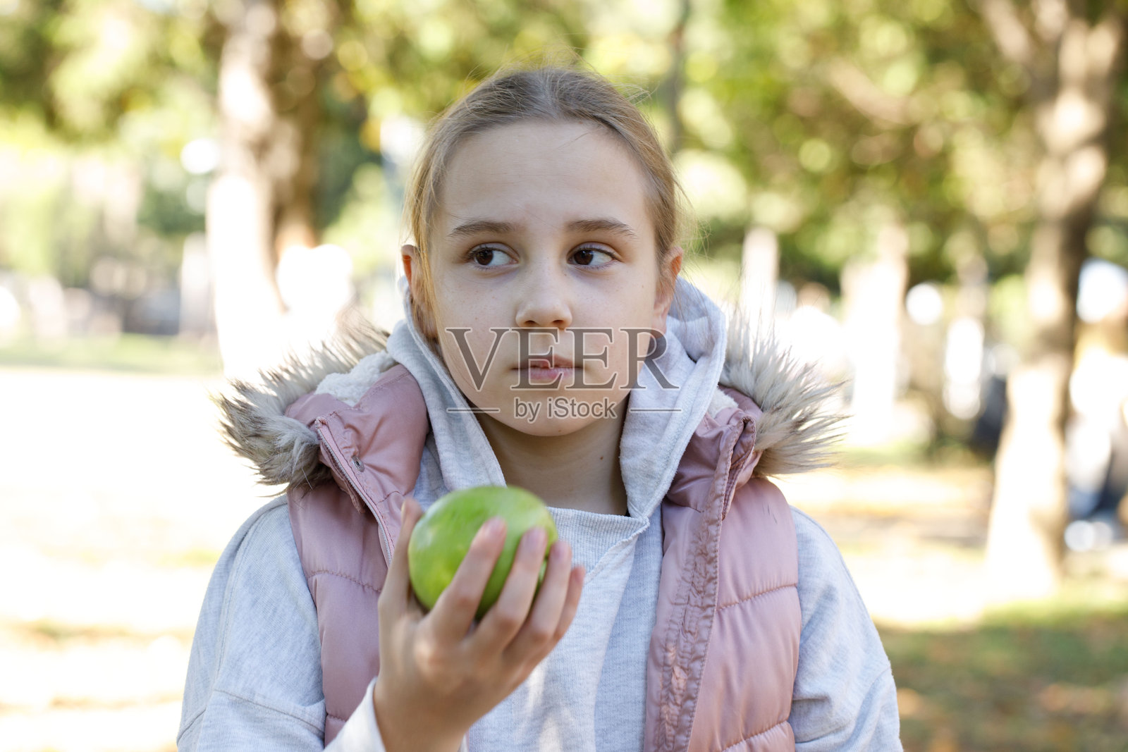 健康的孩子在户外吃苹果。10岁的小女孩。照片摄影图片