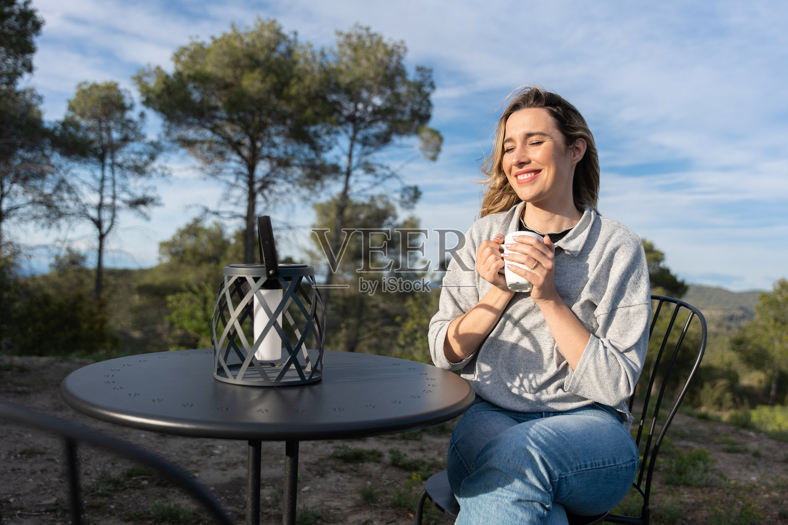 快乐的女人在户外喝热咖啡，冥想并享受风景和新鲜空气，度假时光。照片摄影图片