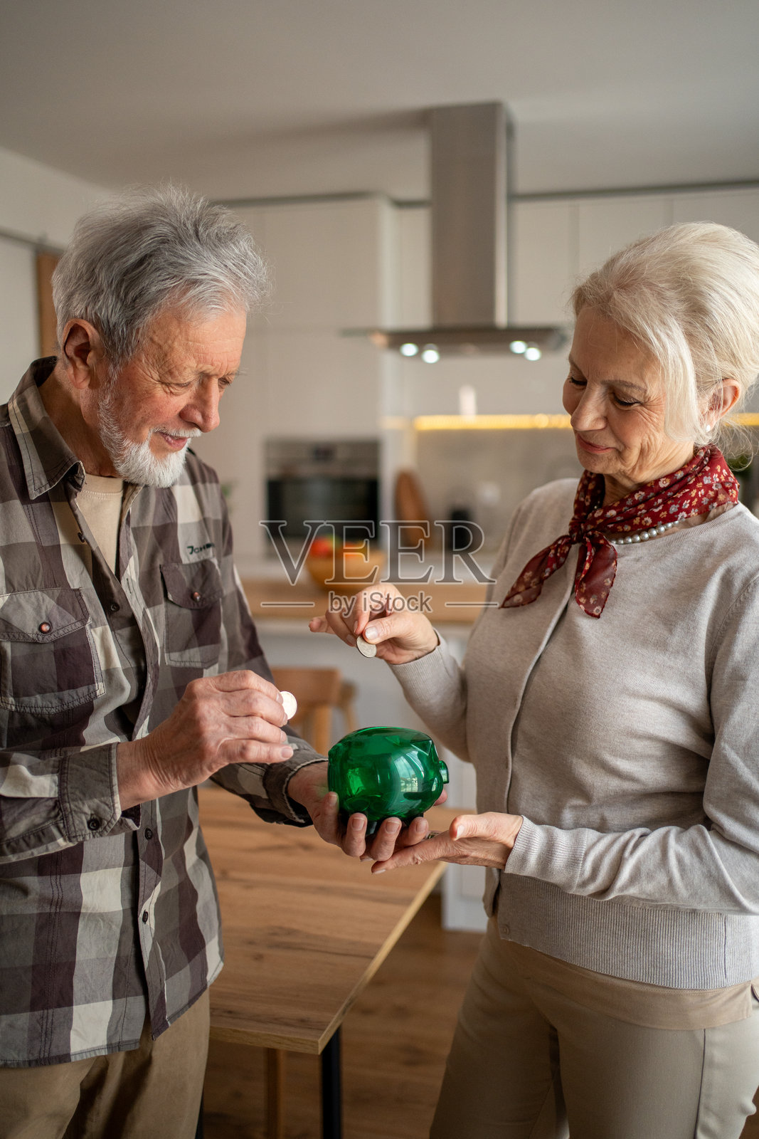 老年夫妇在家里往储蓄罐里投硬币照片摄影图片