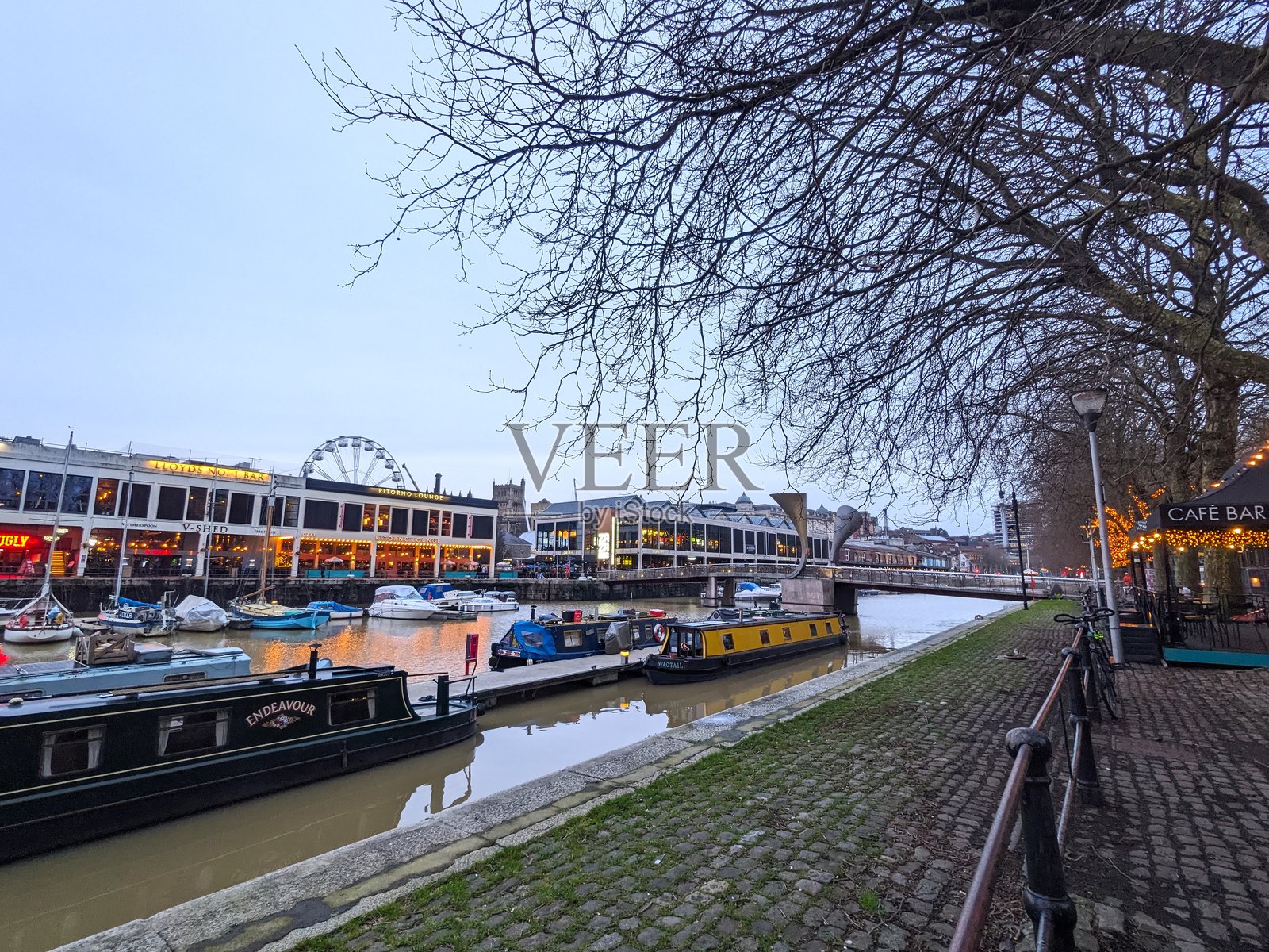 布里斯托历史悠久的浮动港口中停泊着五彩斑斓的船只，夜晚的建筑灯光璀璨。照片摄影图片