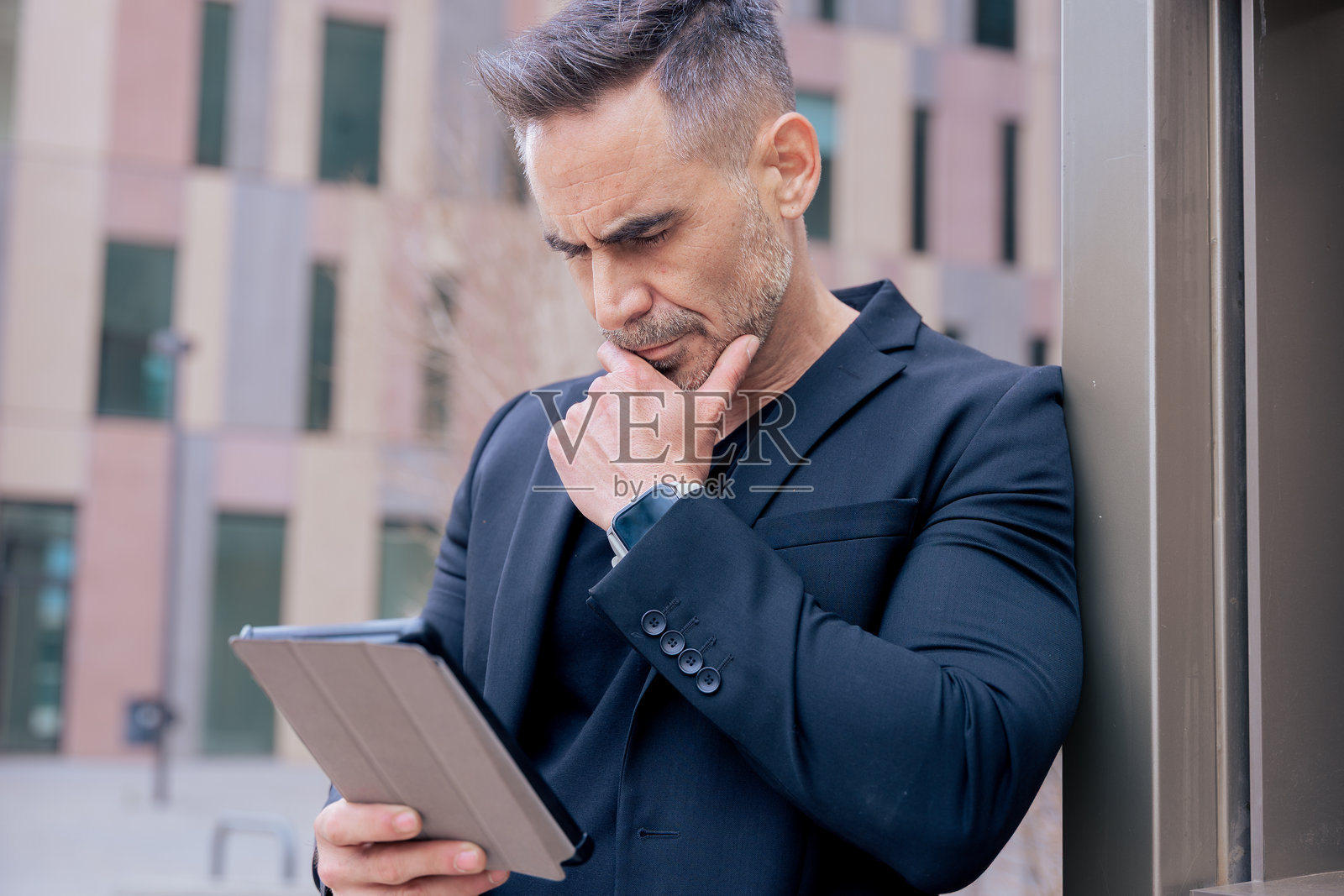 专注于数字信息的思考型商人在户外使用平板电脑照片摄影图片
