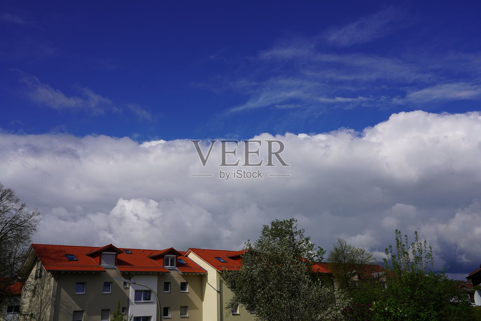 白云在城市上空移动。房屋上方的云朵。白云正逐渐靠近。蓝天和白云在德国上巴伐利亚的巴德艾宾格市上空。照片摄影图片