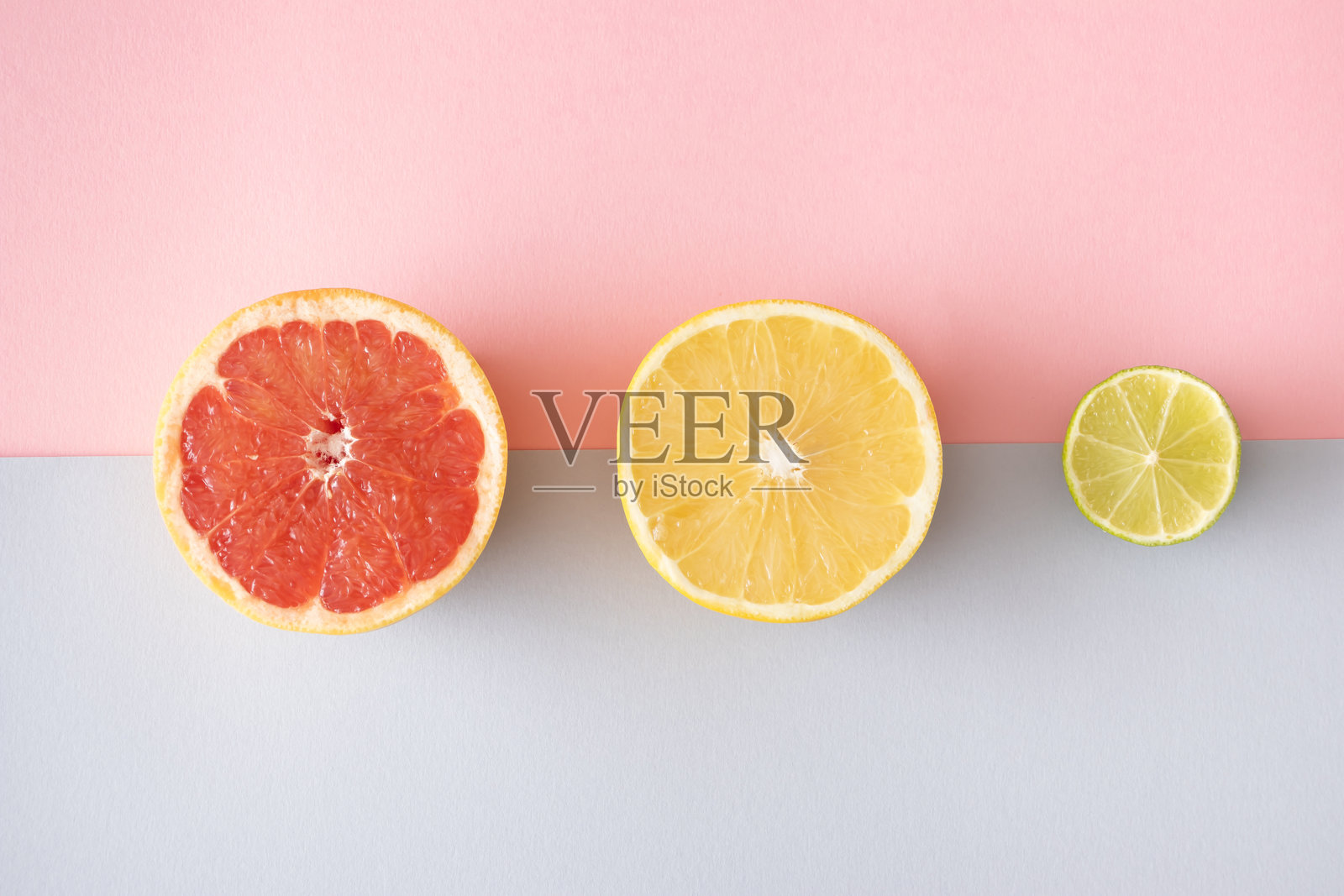 粉红色和灰色背景上的葡萄柚和青柠切片。极简扁平布局。创意概念。照片摄影图片
