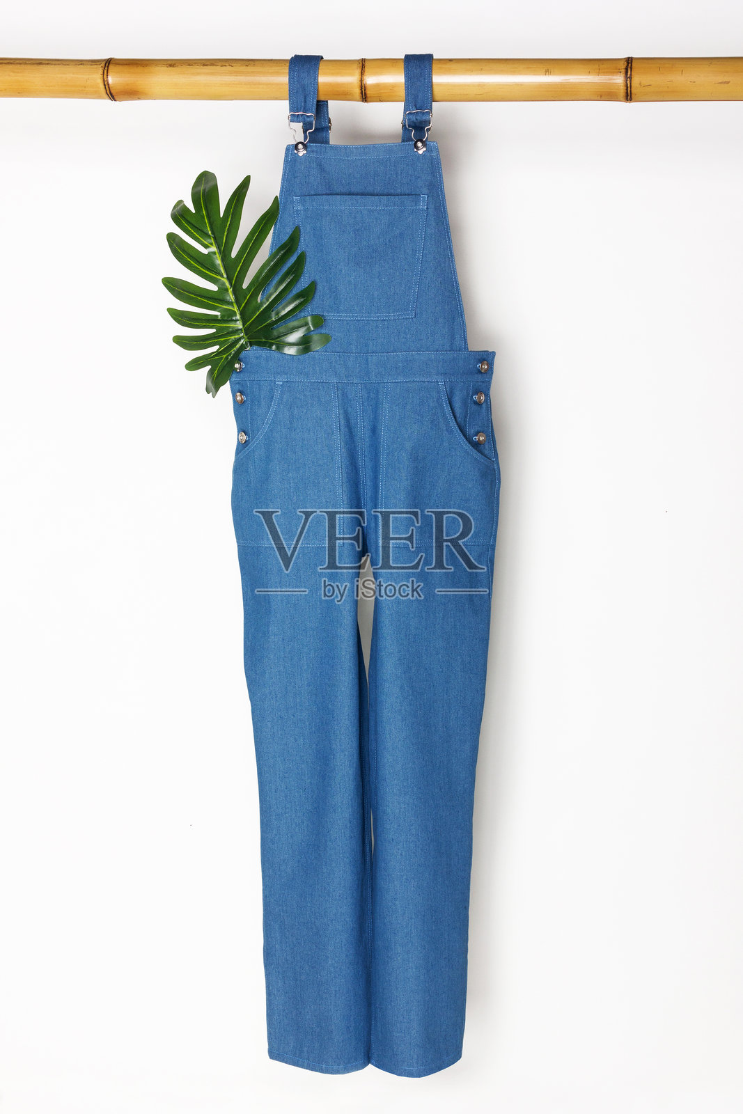 长款牛仔蓝工装裤悬挂在白色背景上照片摄影图片