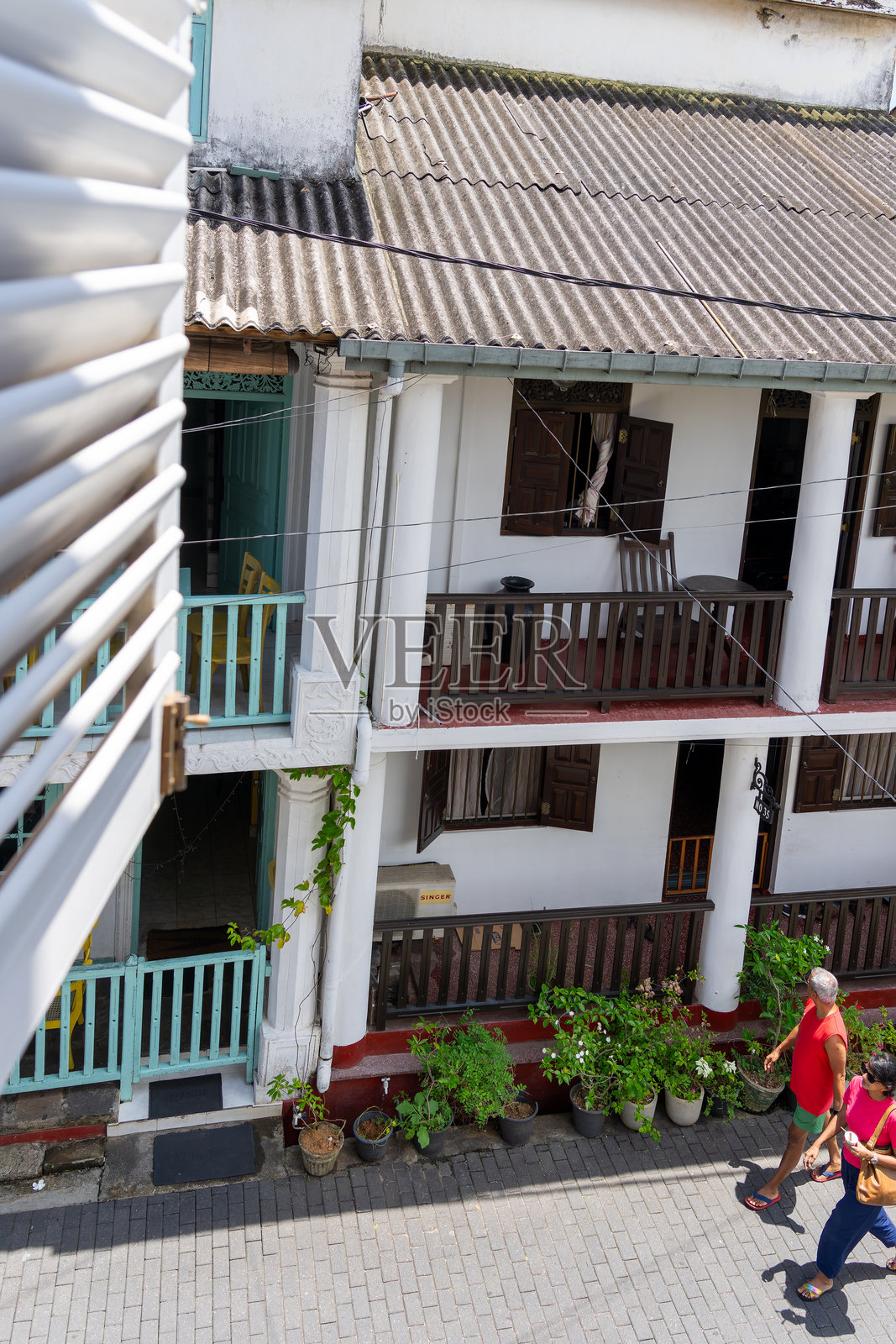 多层公寓外观，带有阳台，游客在下面的街道上经过，俯瞰视角。照片摄影图片