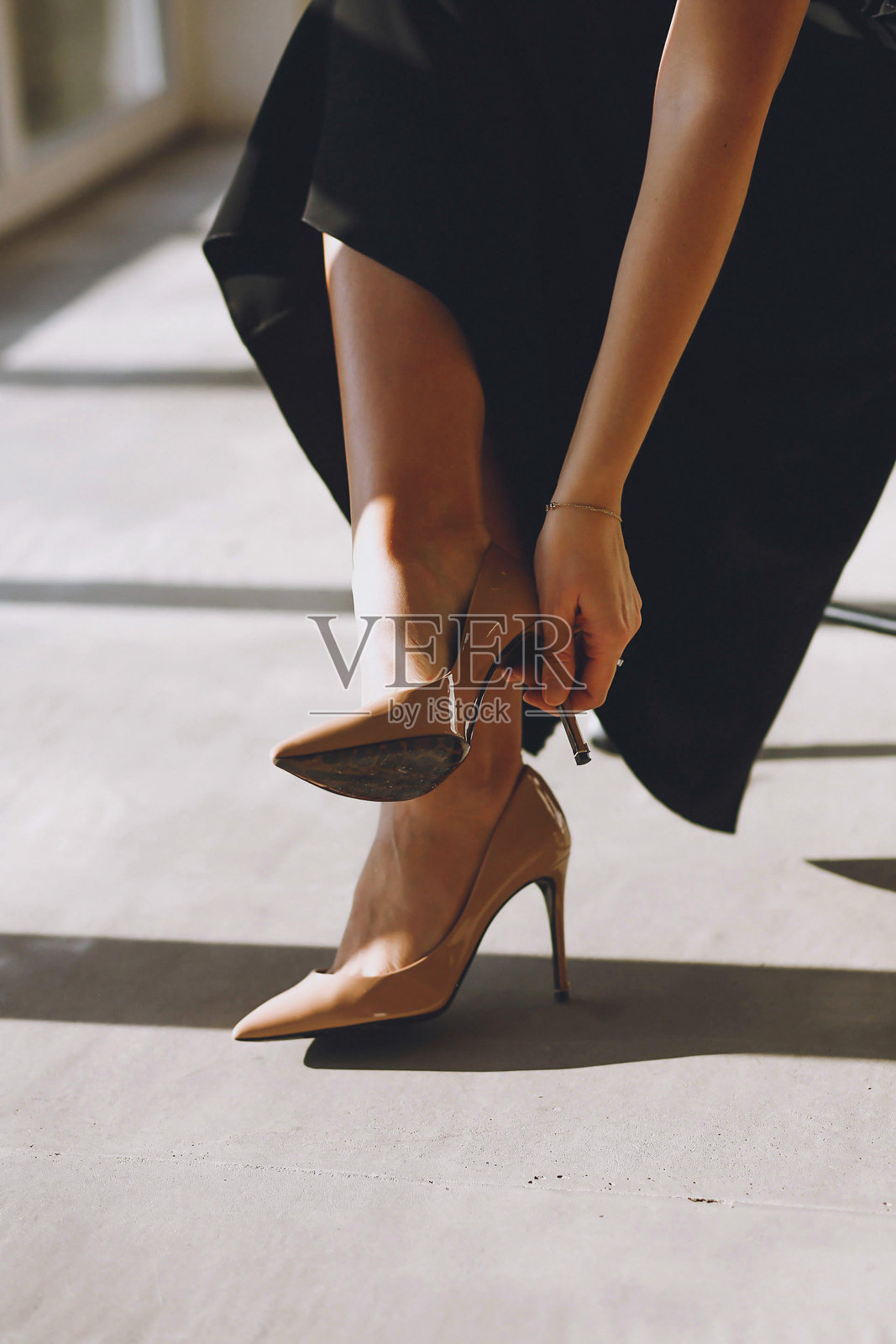 室内一位女性脱掉高跟鞋的特写照片。美丽的女性腿部。照片摄影图片
