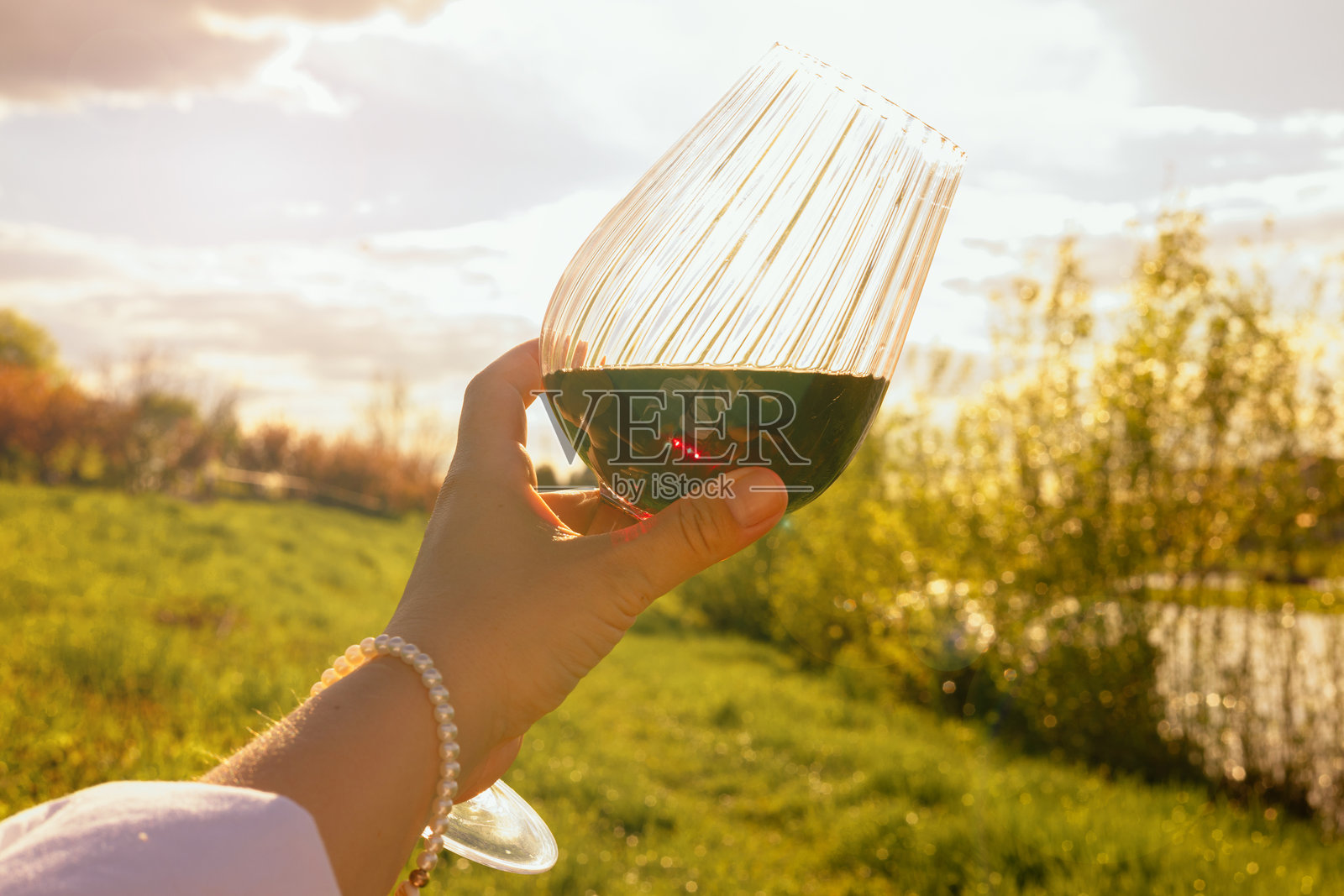 女人手中拿着一杯酒，背景是自然风光照片摄影图片