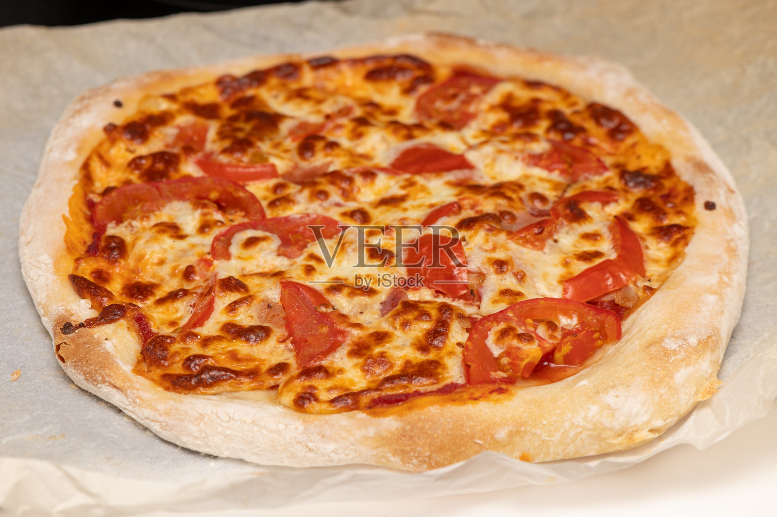 美味自制披萨的特写镜头，上面铺满了酥脆的培根、融化的奶酪和新鲜的番茄。非常适合烹饪网站和食品推广。照片摄影图片