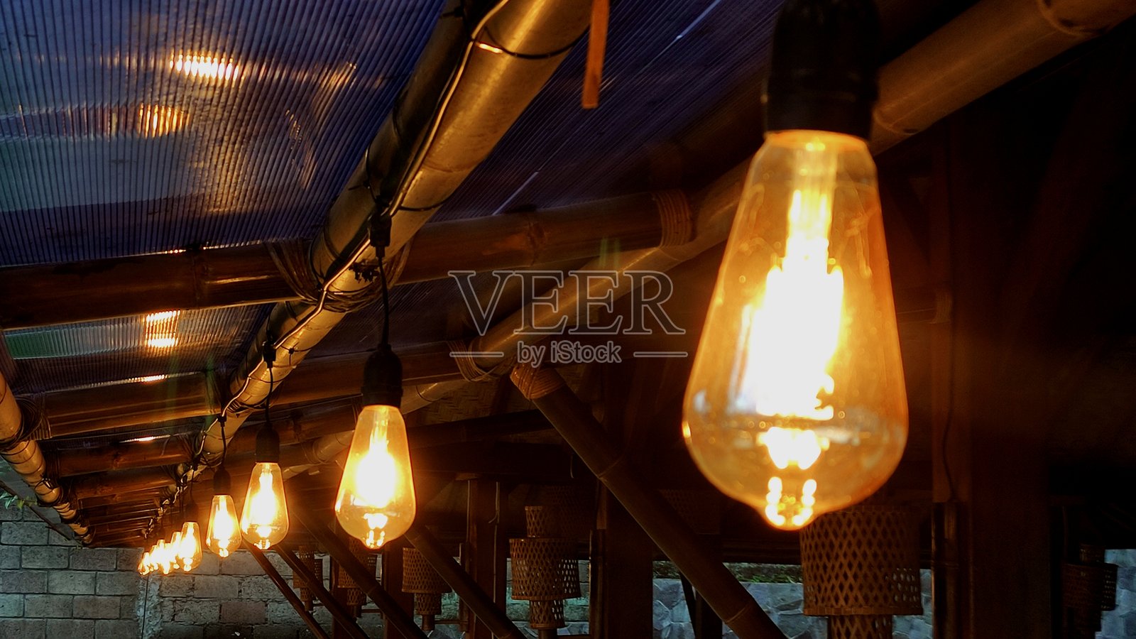 模糊的派对酒吧或酒馆背景下悬挂的黄色橙色灯光灯具照片摄影图片