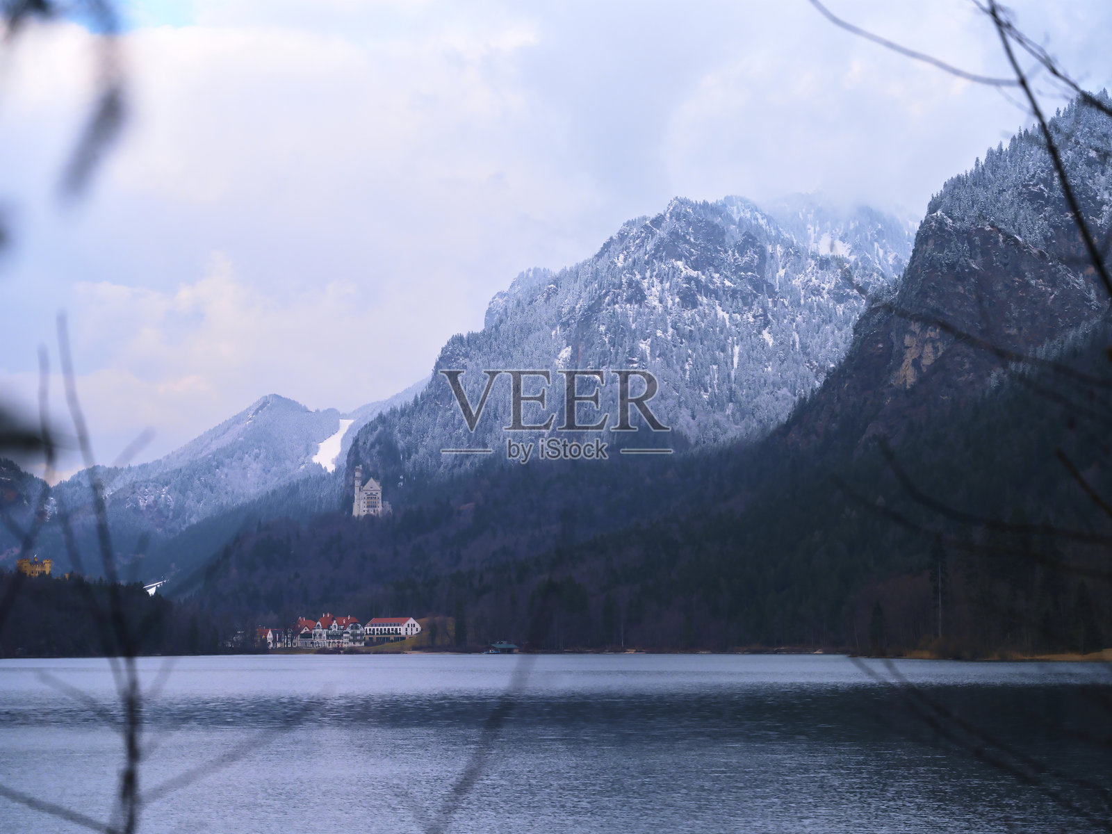 雪山倒映在宁静的湖面上，附近是一家古雅的度假村，寒冷的冬日里显得格外迷人。照片摄影图片