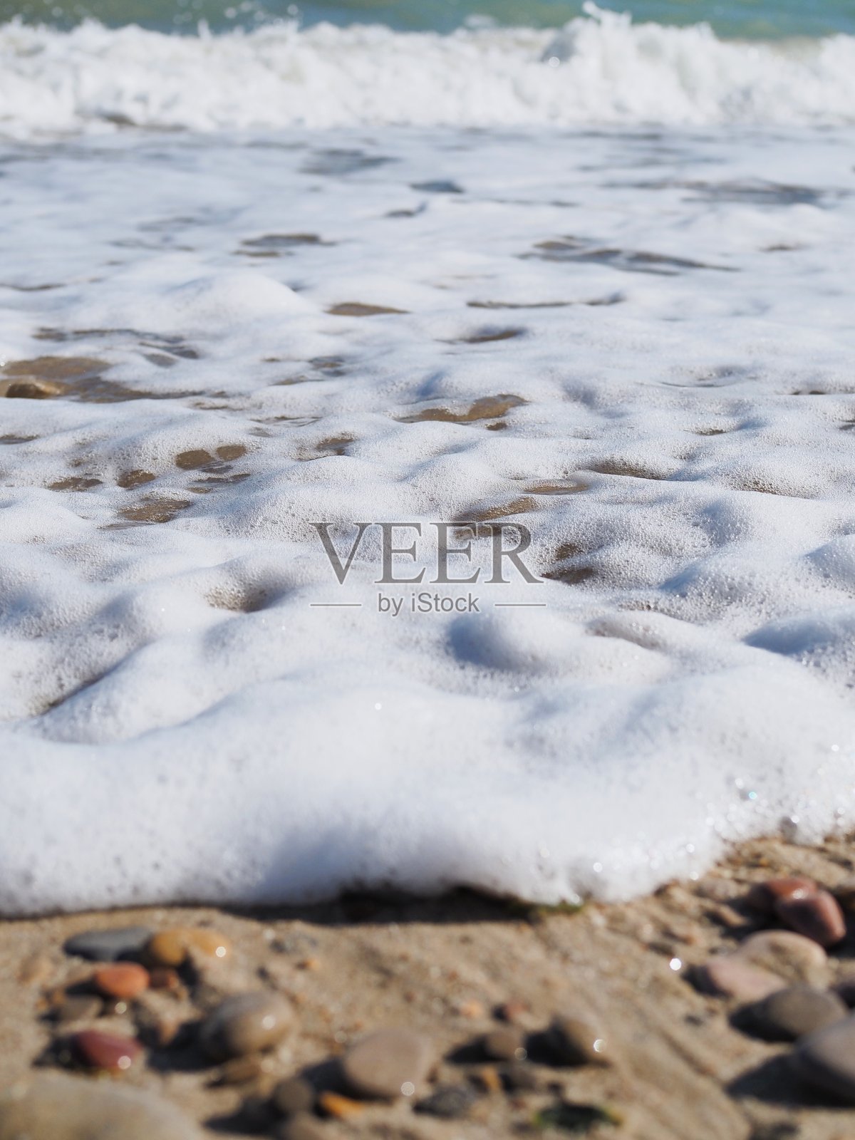 鹅卵石海滩的特写镜头和白色泡沫照片摄影图片
