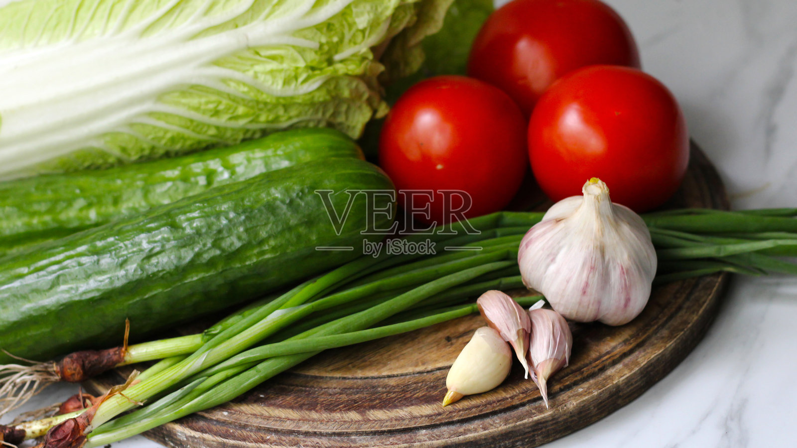 新鲜的沙拉蔬菜。大蒜、黄瓜和西红柿，适合健康午餐。照片摄影图片