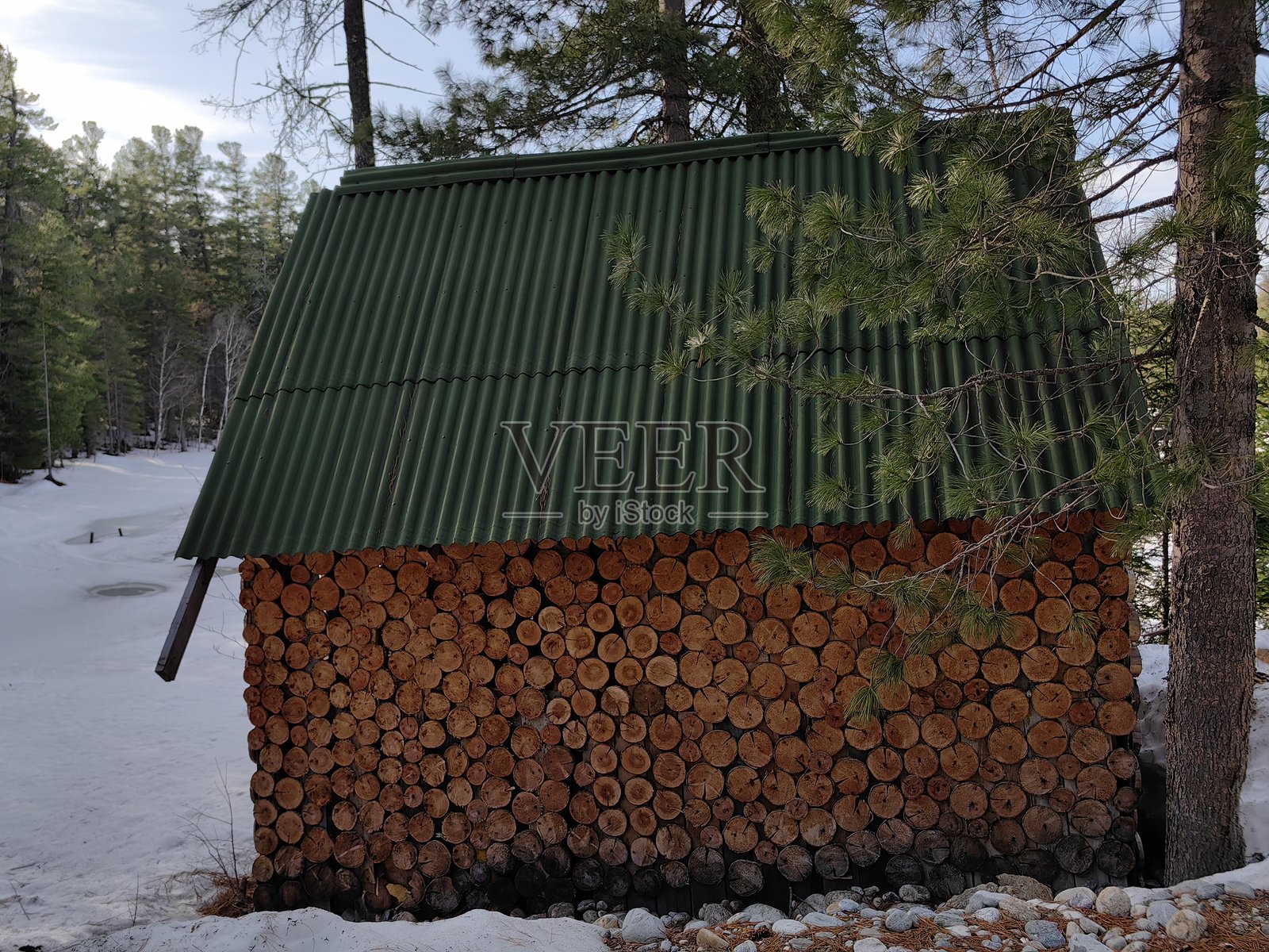 装饰性切割木材和绿色屋顶的木屋，四周被冬季森林中的雪覆盖。照片摄影图片