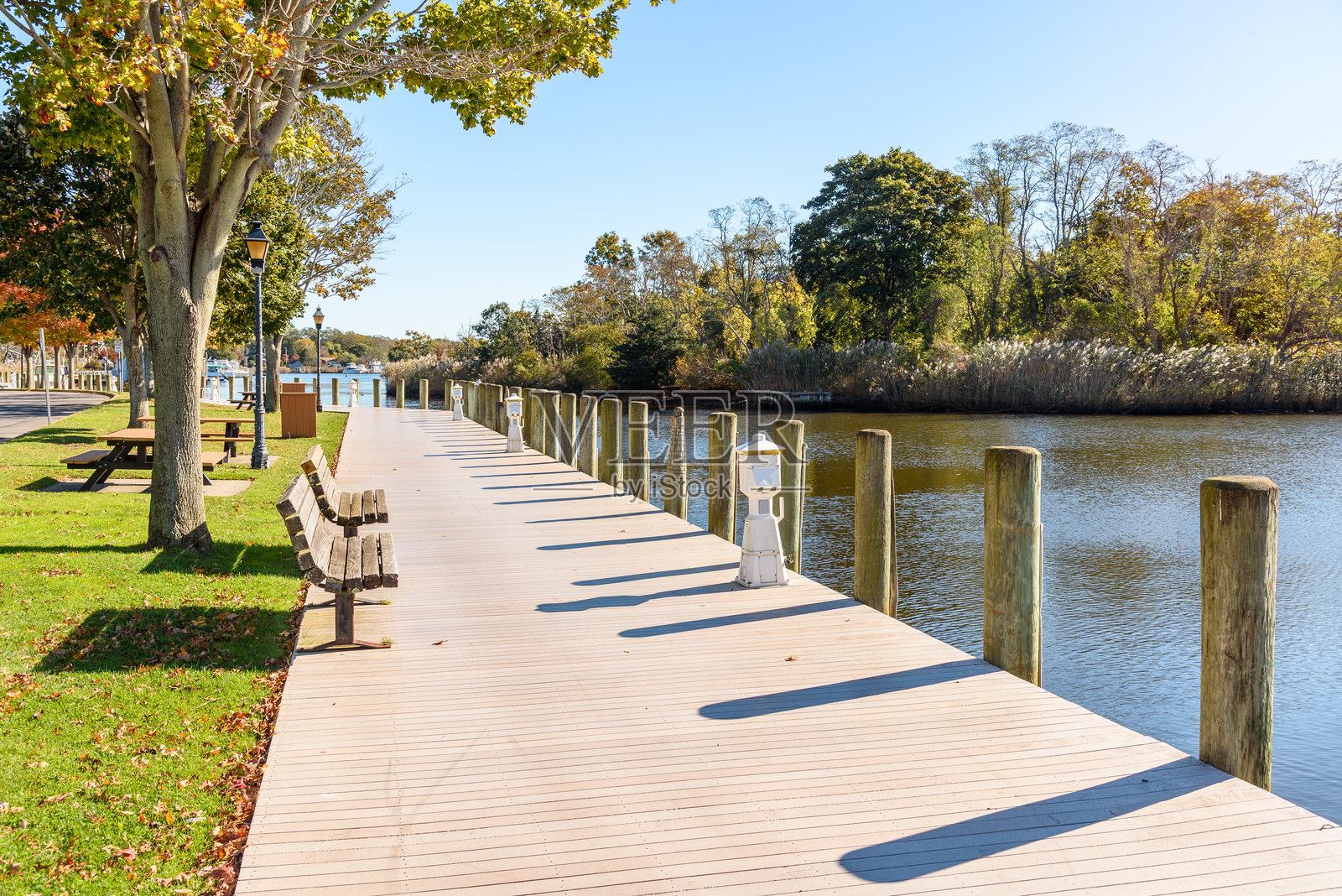 阳光明媚的秋晨，河港旁的荒废木栈道在晴朗的天空下照片摄影图片