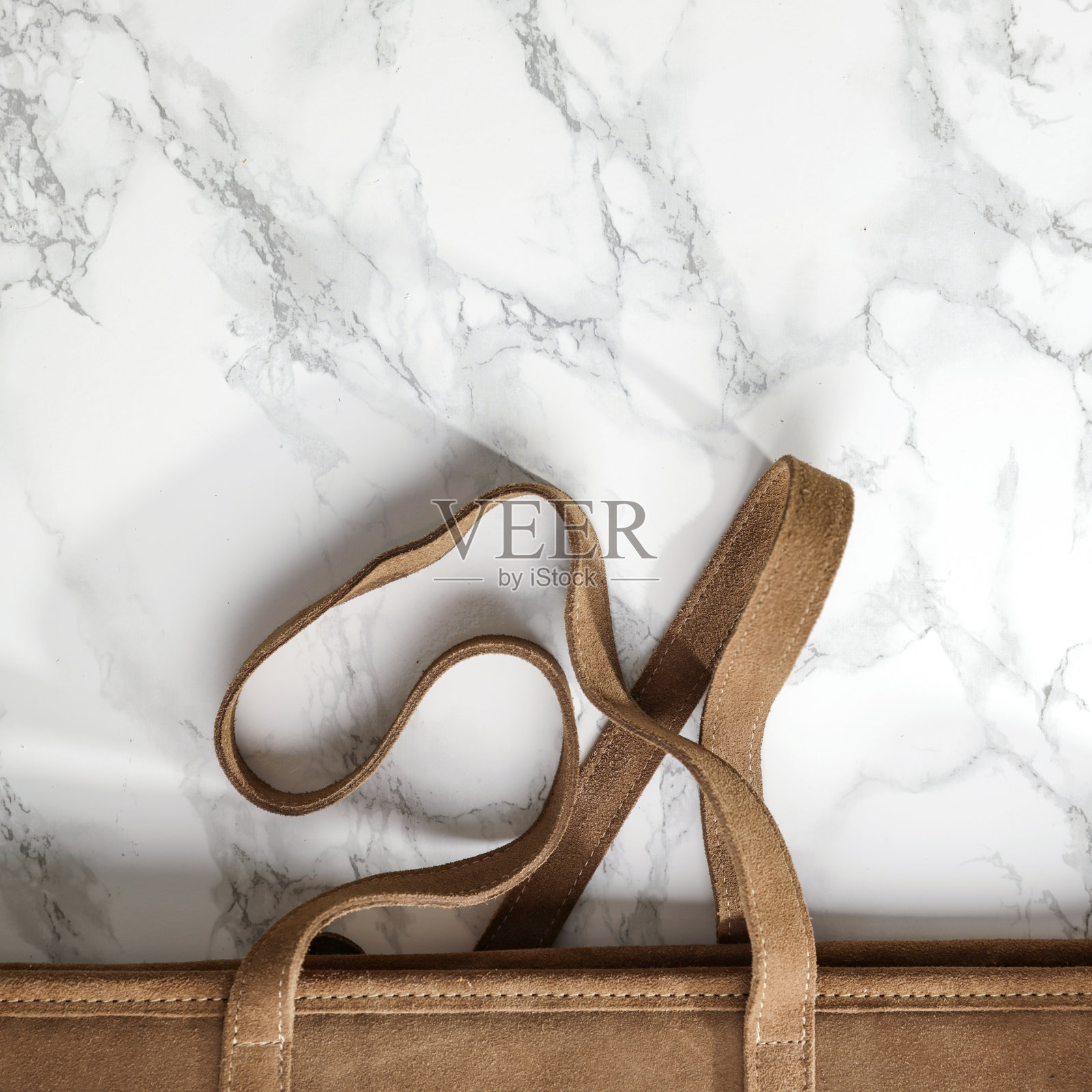 优雅的平铺布局，棕色包包置于白色大理石背景上 - 浪漫的女性构图，留有空白空间供文本或产品使用。非常适合设计项目。照片摄影图片