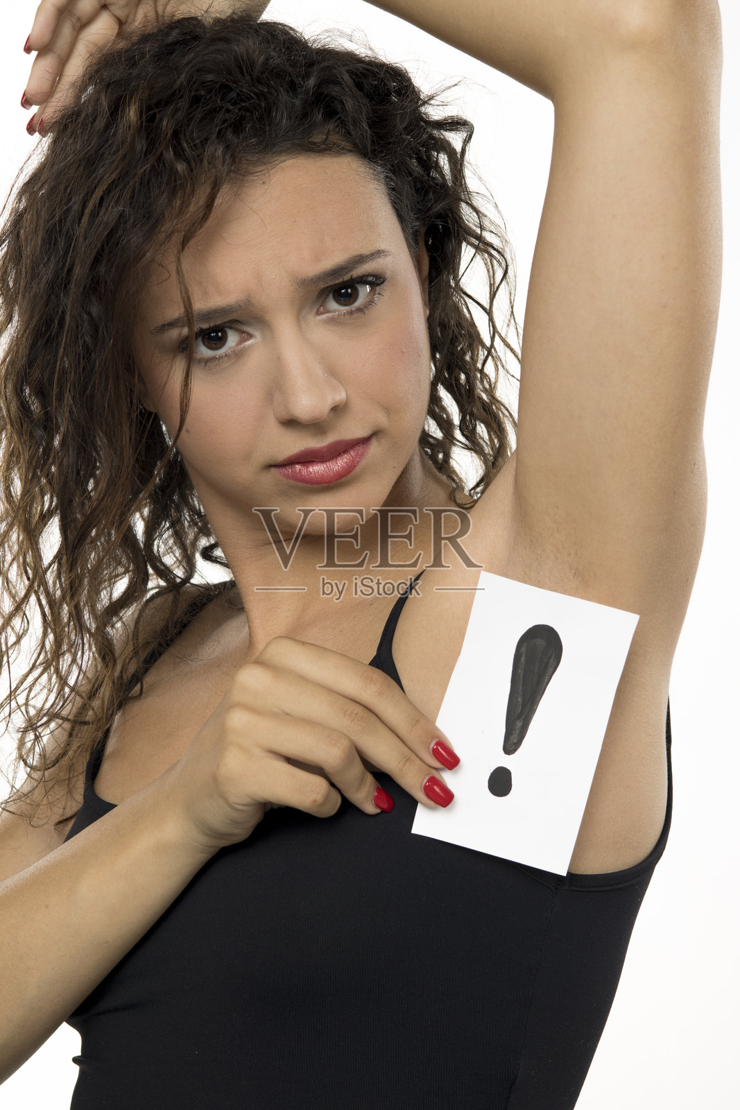 年轻女性面露担忧，手持带有感叹号的卡片。腋毛去除概念。白色背景下的工作室肖像展示护肤困境。照片摄影图片
