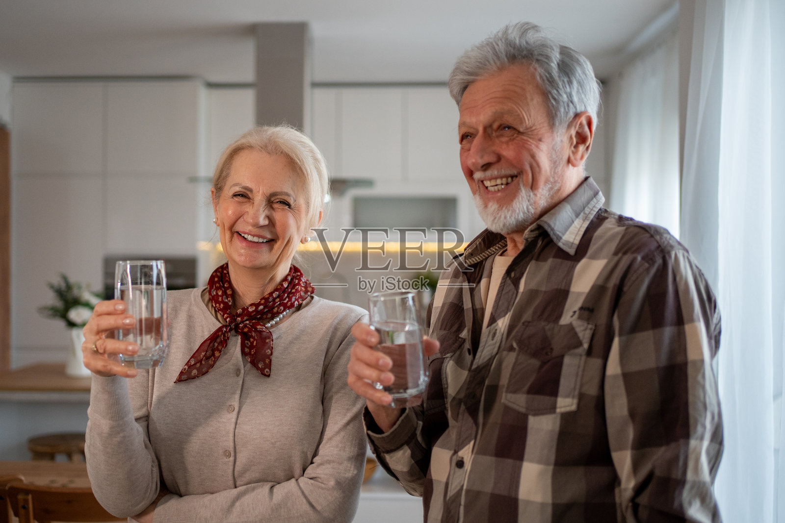 快乐的老年夫妇在厨房里喝水并微笑照片摄影图片
