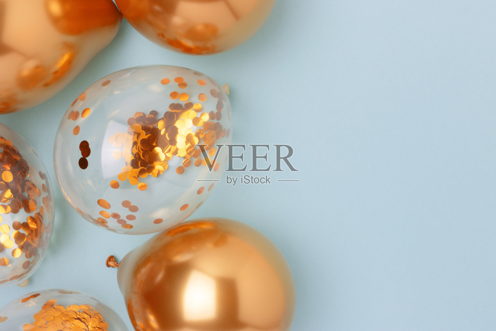 蓝色背景上的金色充气气球，里面装满了五彩纸屑。照片摄影图片