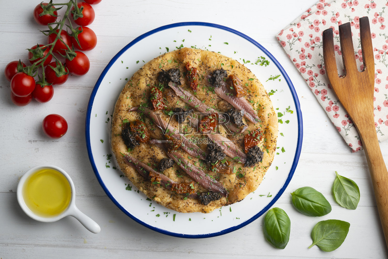 正宗意大利佛卡夏，配有咸鳀鱼、晒干番茄和黑橄榄。顶部视角的桌子上摆放着圣诞装饰。照片摄影图片