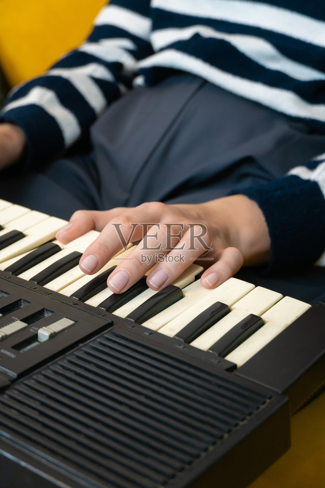 手指在复古合成器的键盘上舞动，创造出复杂的旋律和丰富的电子音效，展现出一位专注音乐家的技巧与热情。竖版照片照片摄影图片