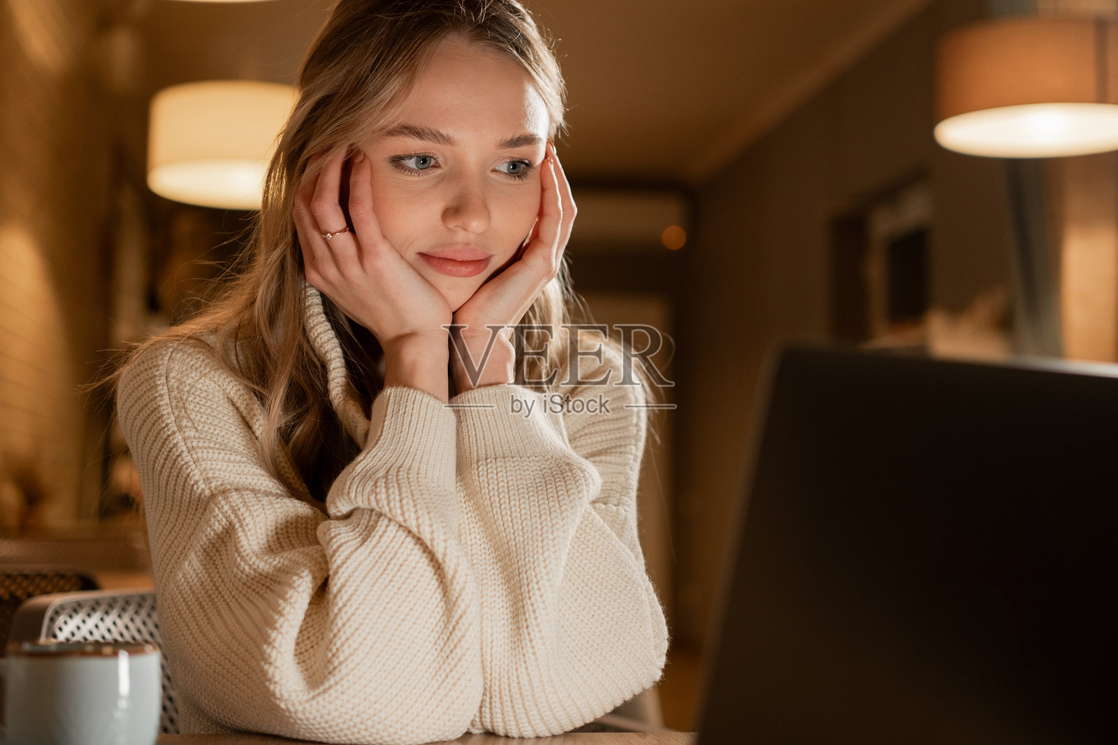 疲惫的女性在咖啡馆用笔记本电脑工作，双手托着头，盯着屏幕，观看网络研讨会并在咖啡馆做作业。照片摄影图片