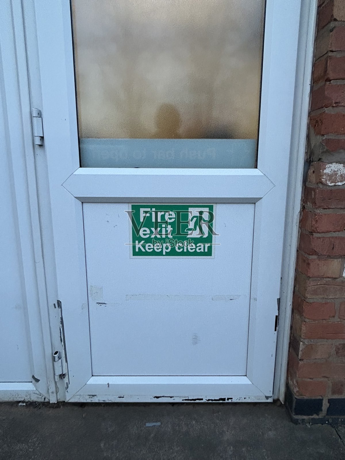 白色UPVC门上有绿色消防出口标志照片摄影图片