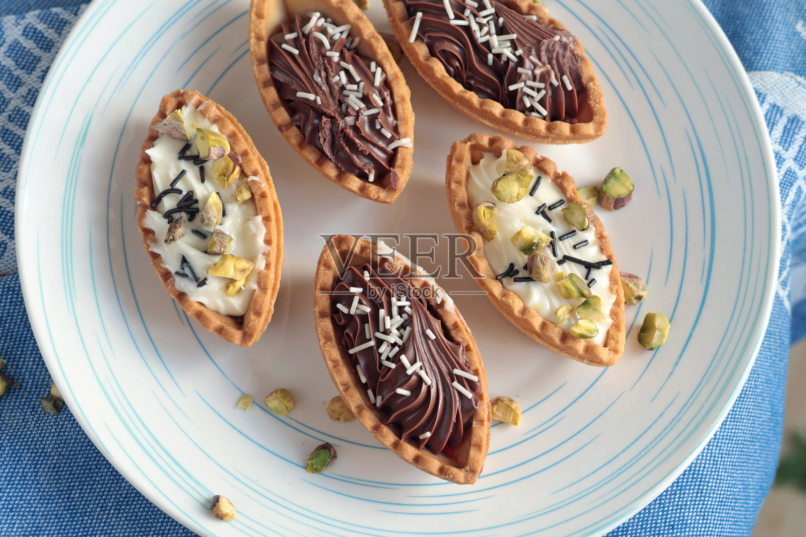 白盘上的沙面团挞，内含巧克力馅，顶部撒有开心果。照片摄影图片