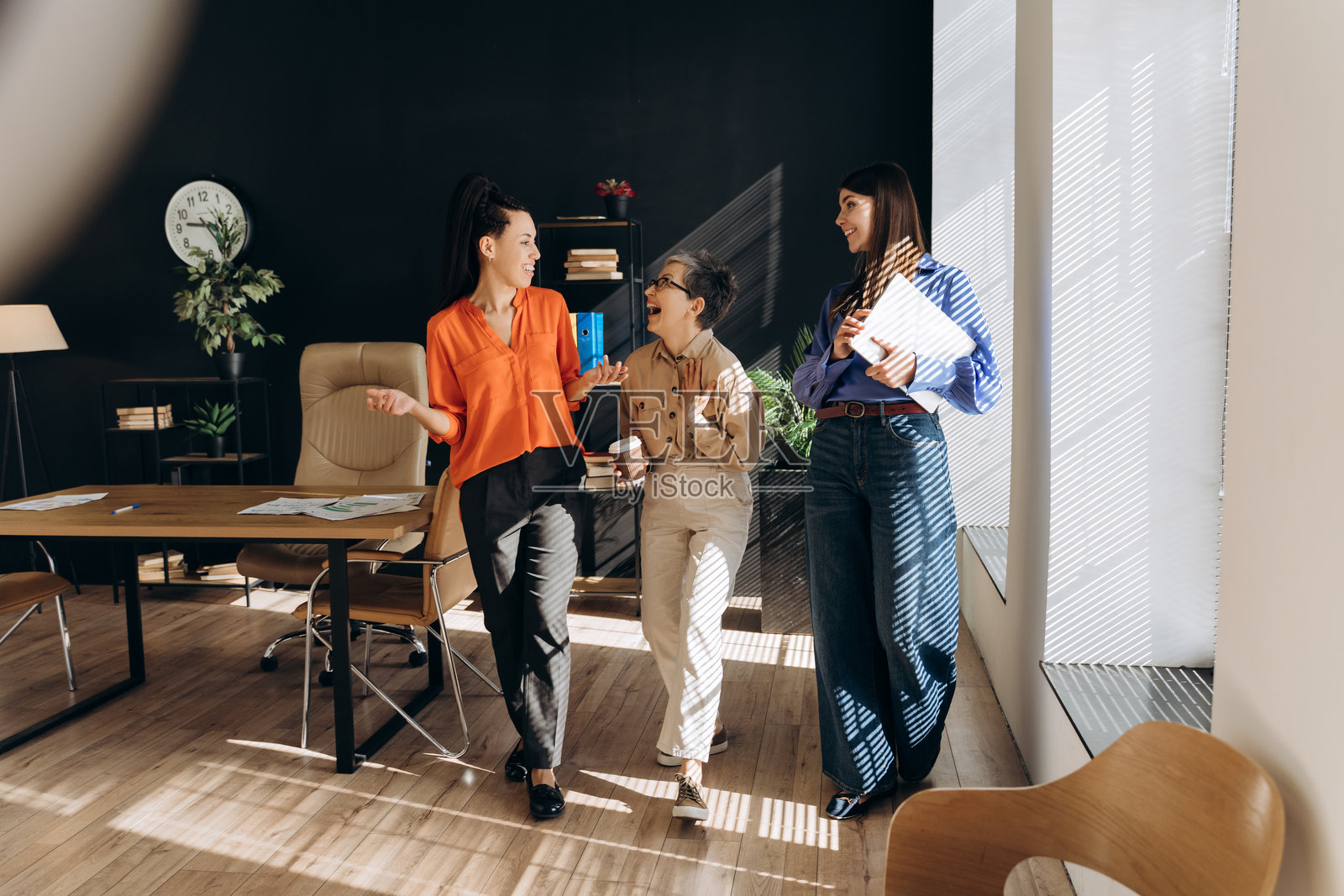 微笑的跨国女商人在现代办公室中分享想法并欢笑在一起照片摄影图片