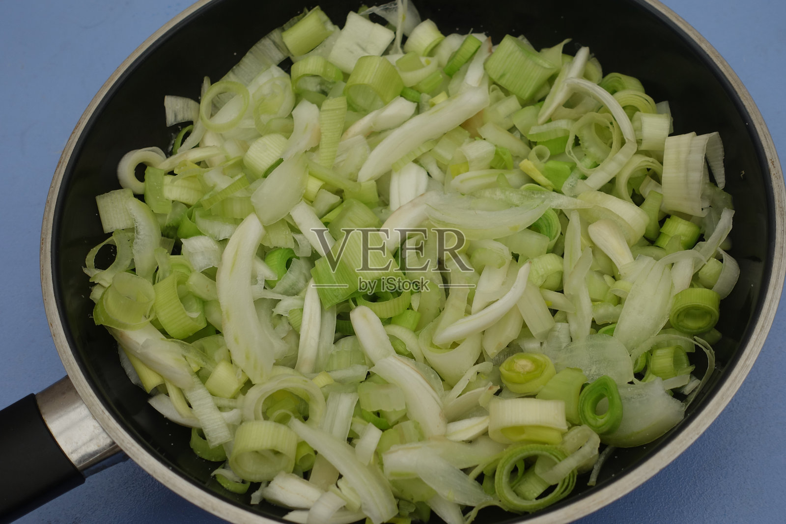 在荷兰锅中准备用茴香、韭葱和洋葱制作的蔬菜装饰，正在烹饪中。照片摄影图片