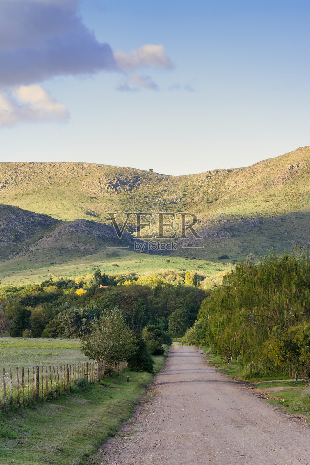 蜿蜒的土路通向日落时分的起伏山丘照片摄影图片