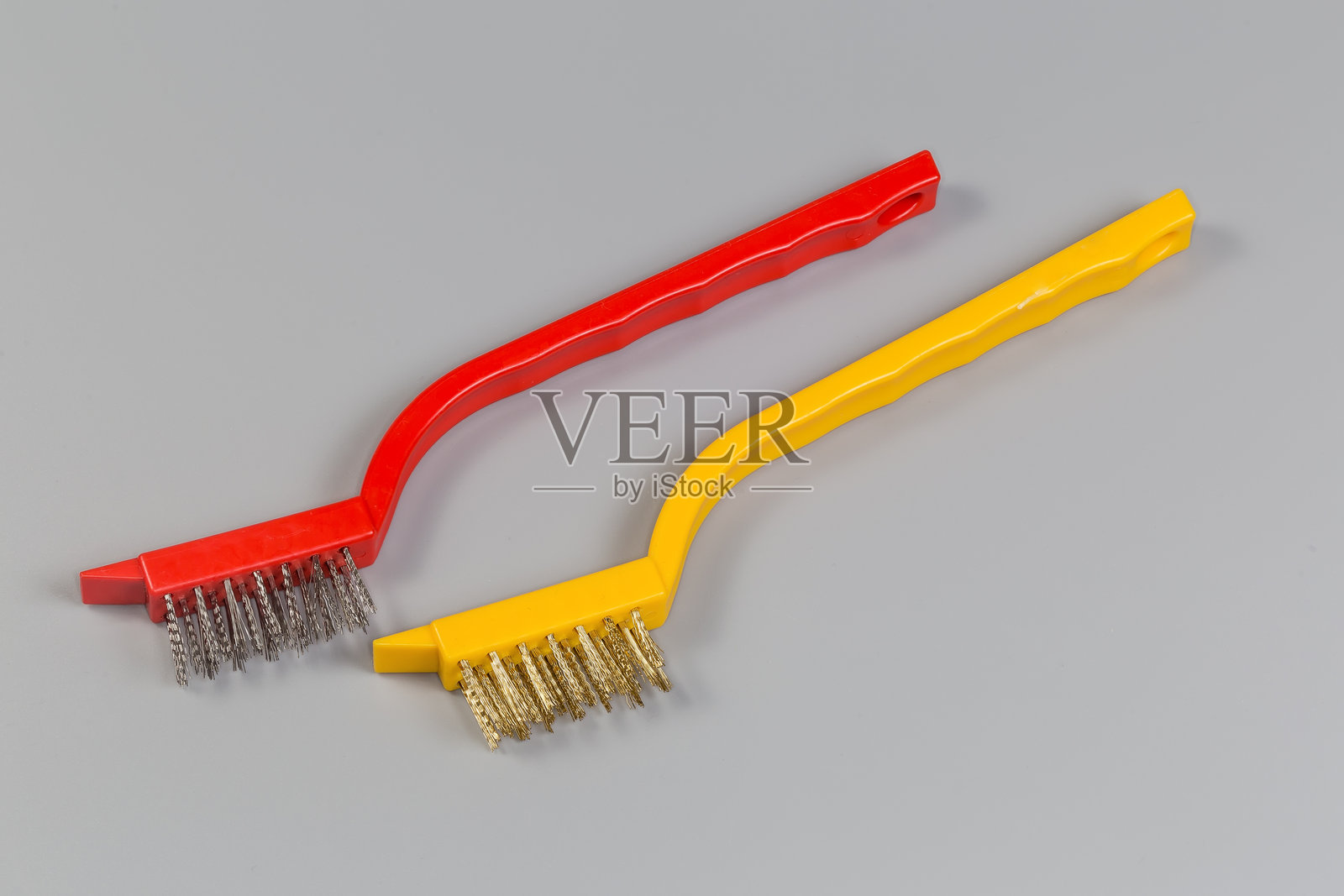 两把带塑料手柄的手动钢丝刷，背景为灰色照片摄影图片