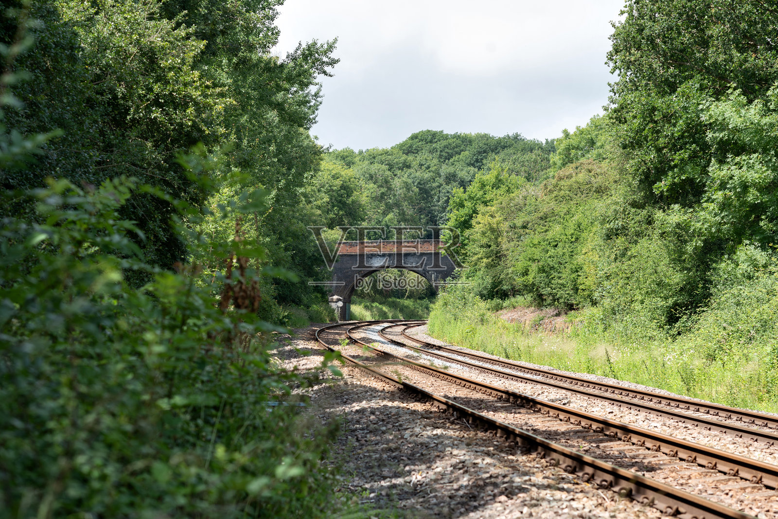 阳光明媚的日子里，通往桥的双轨铁路。照片摄影图片